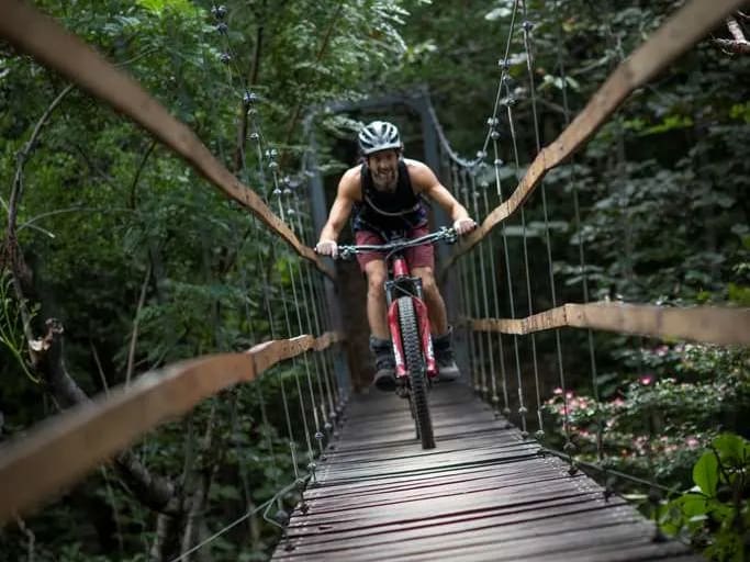 A man rides a bike across a bridge at Río Perdido Hotel & Thermal River