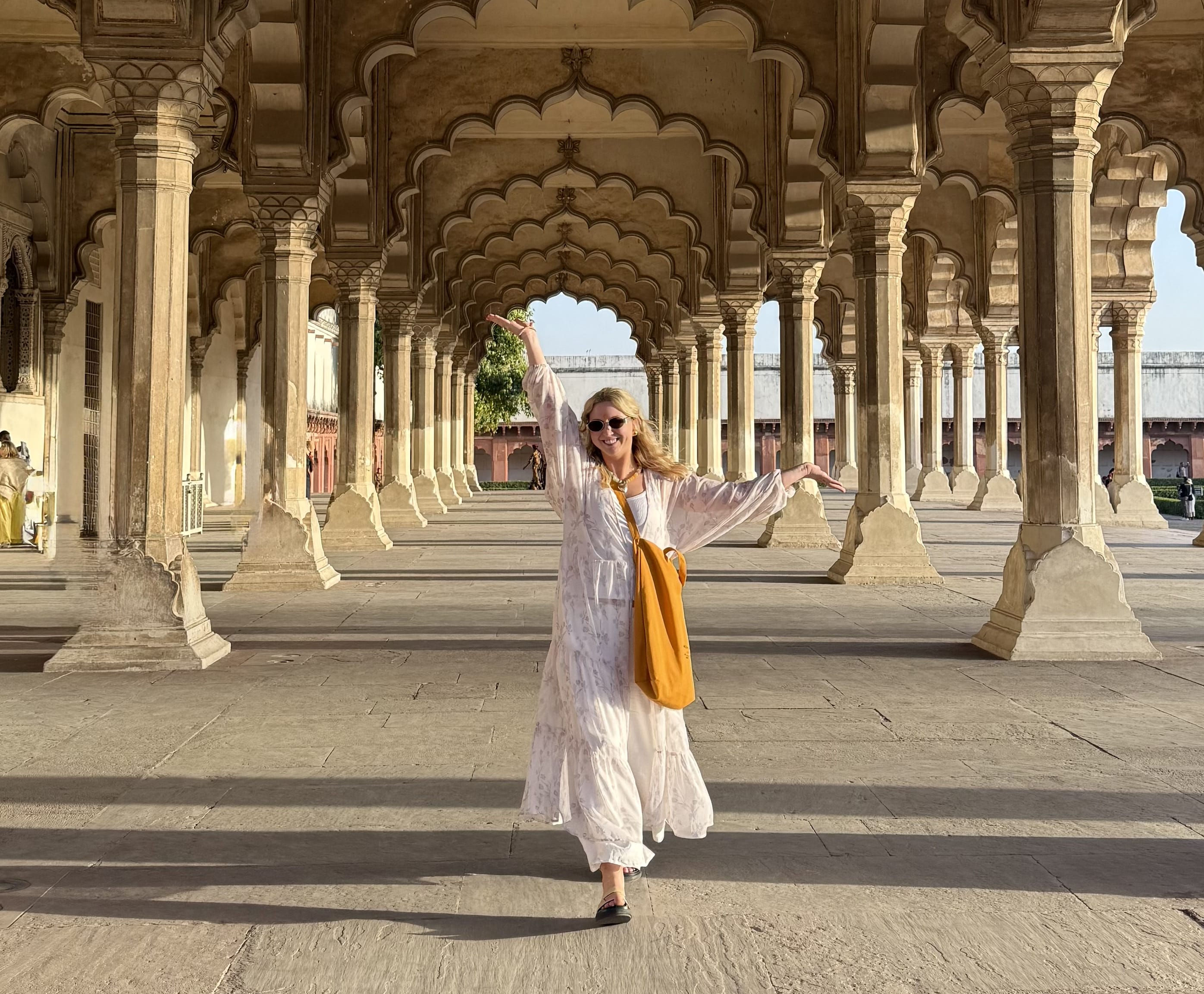 a woman in a white dress stands under an arched walkway