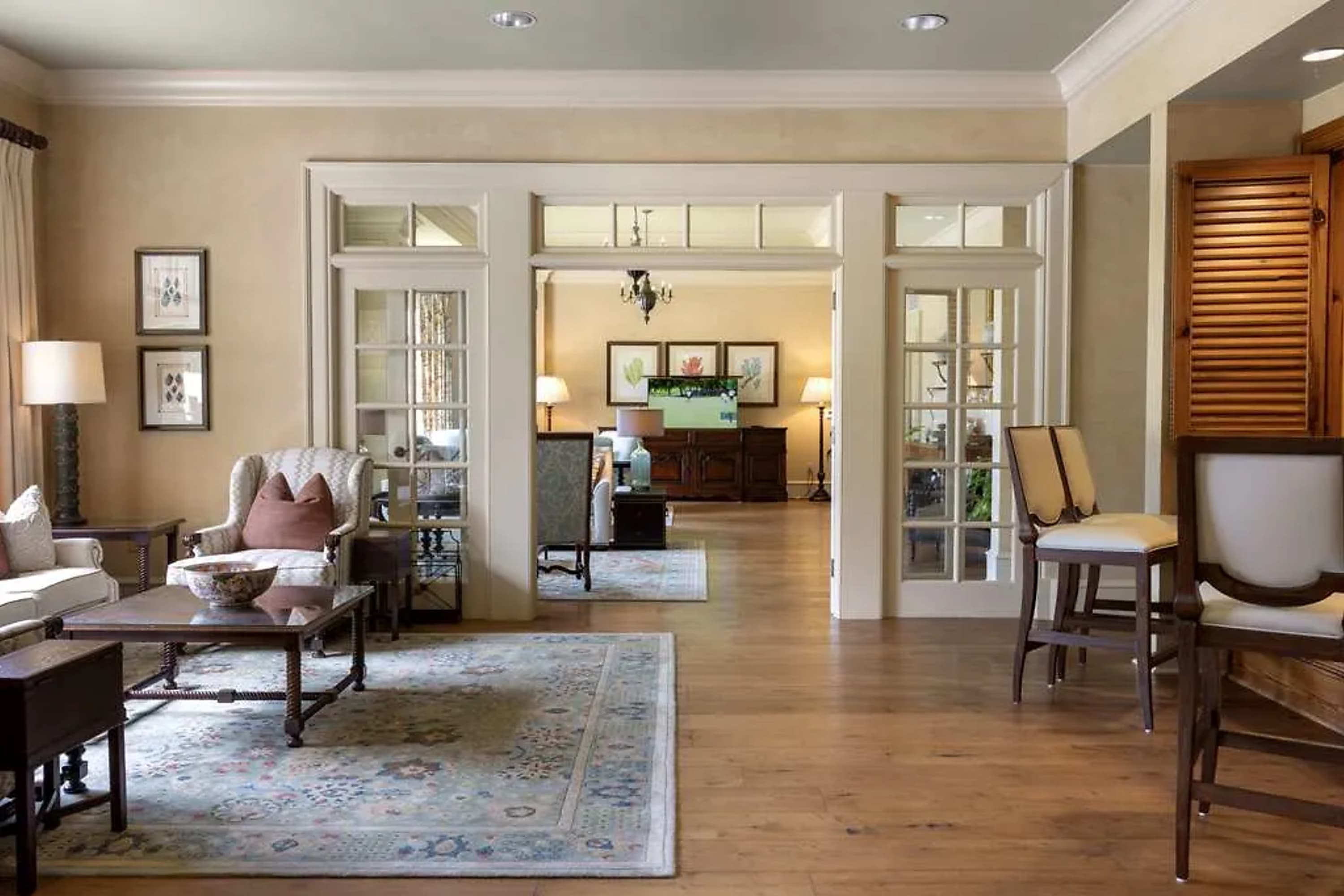Classical Southern decor in a spacious suite, distinct living and sleeping areas evident, and a golf game on TV in the back