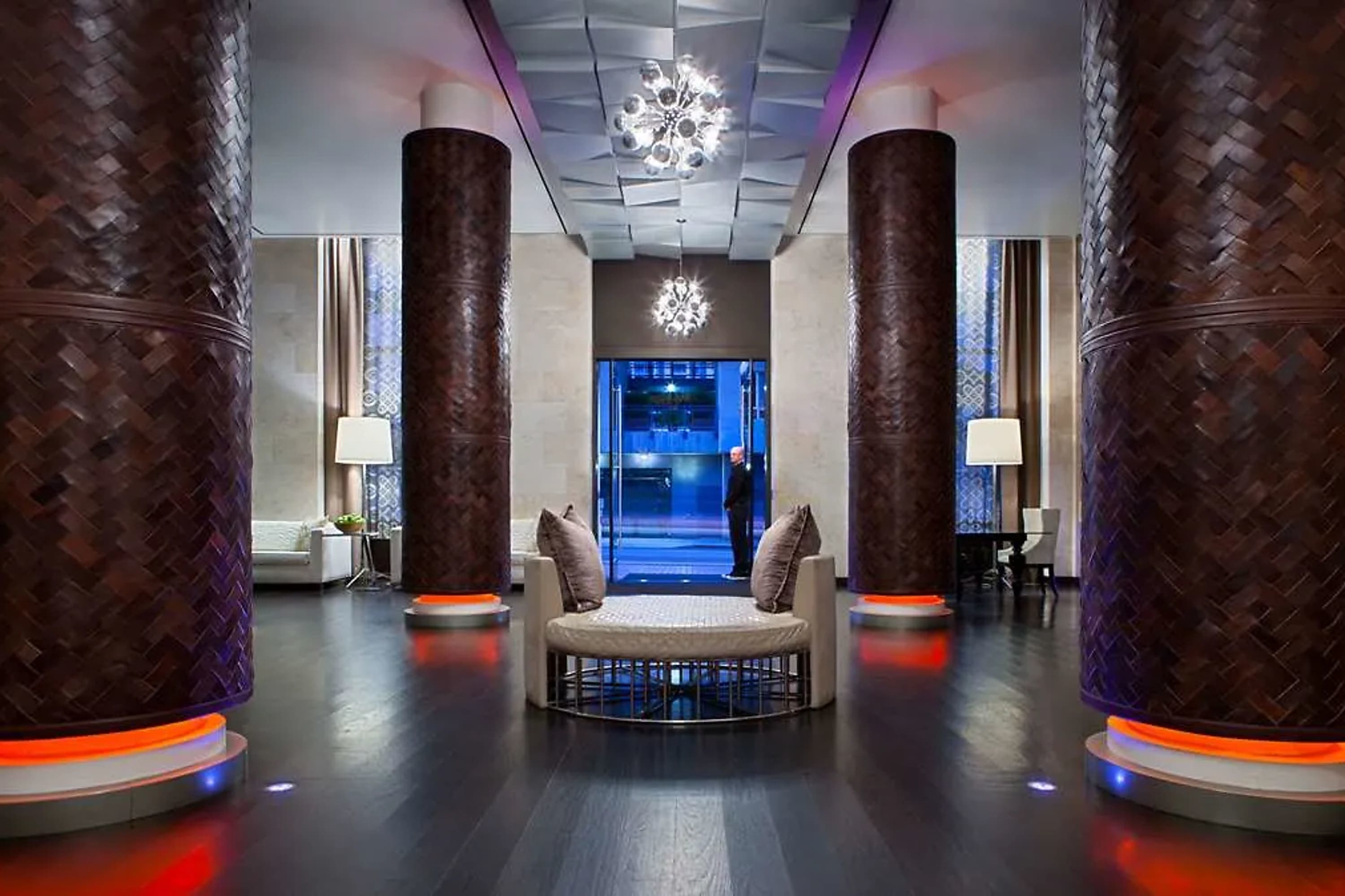 Chic, contemporary lobby with orange neon accents contrasting with bright, white chandeliers