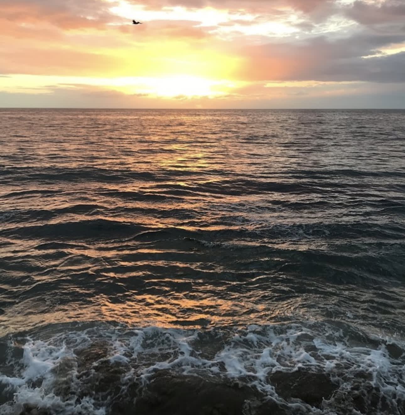 View of sea waves and a sunset in the background