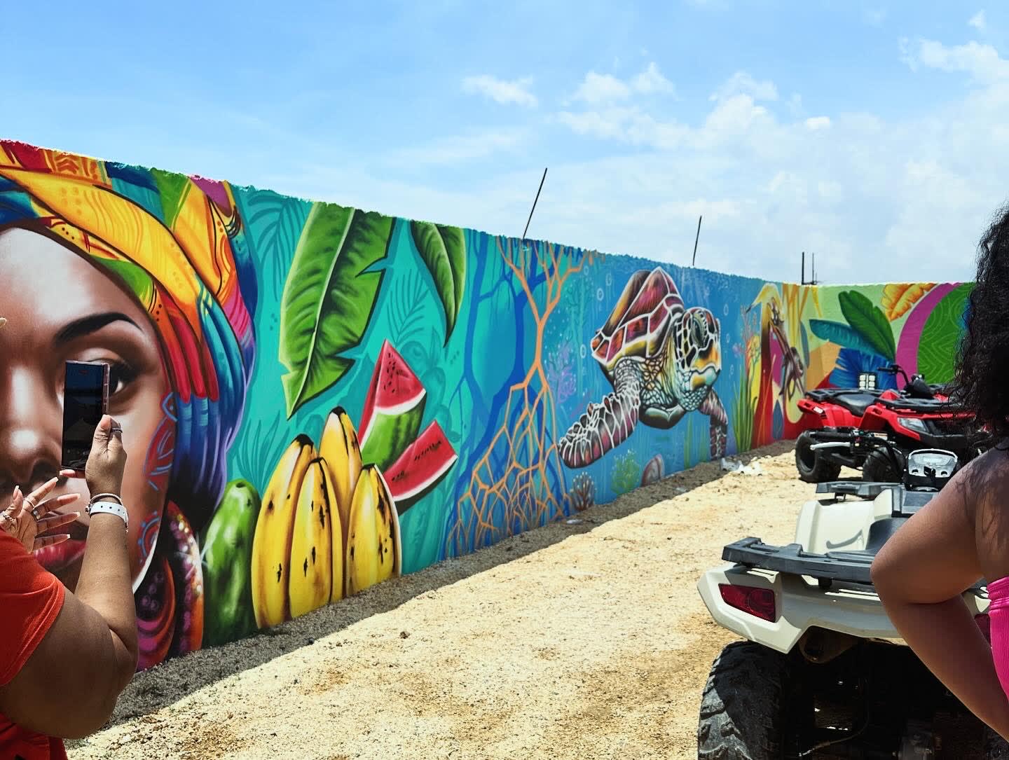 A bright colored mural depicting a woman, fruit and a sea turtle