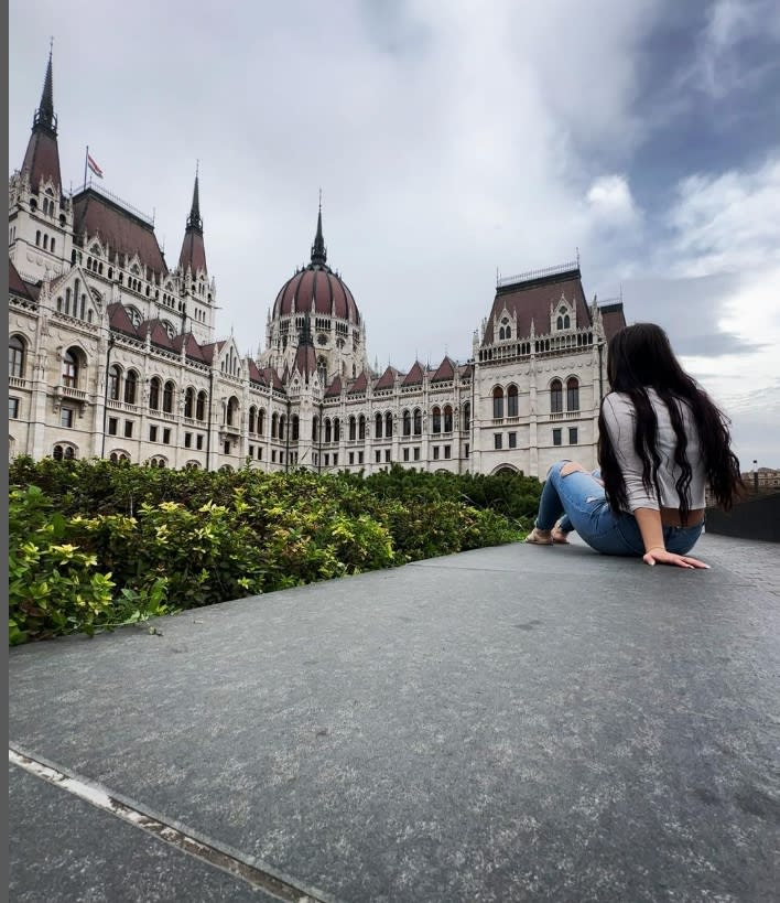 Olga sitting on a curb looking at the Hungarian Parliament Building