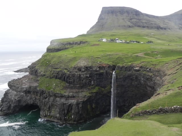 A picture of green cliffs with the ocean in view