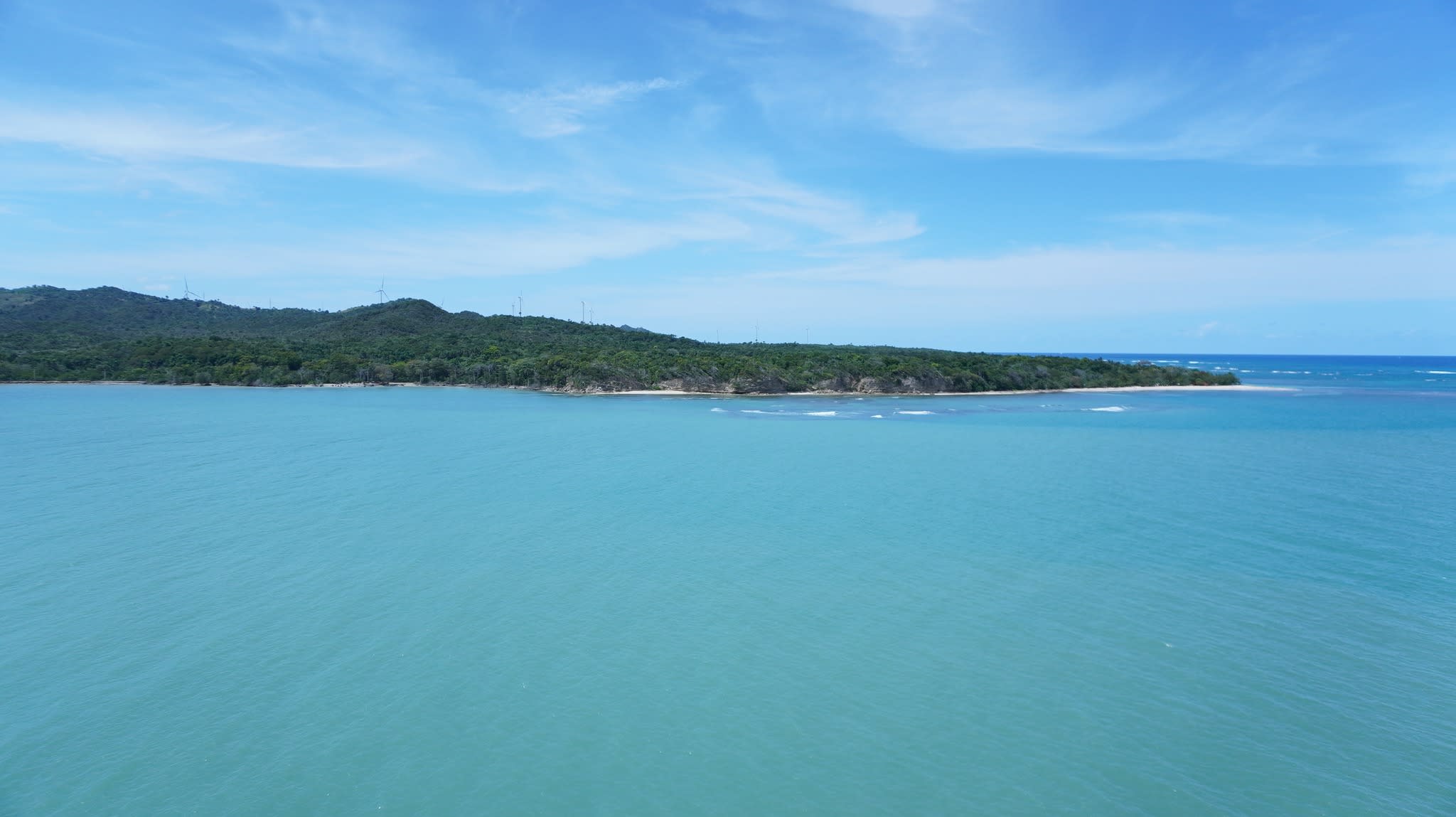 Beautiful view of a bright turquoise sea under a blue sky with a green piece of land in the distance