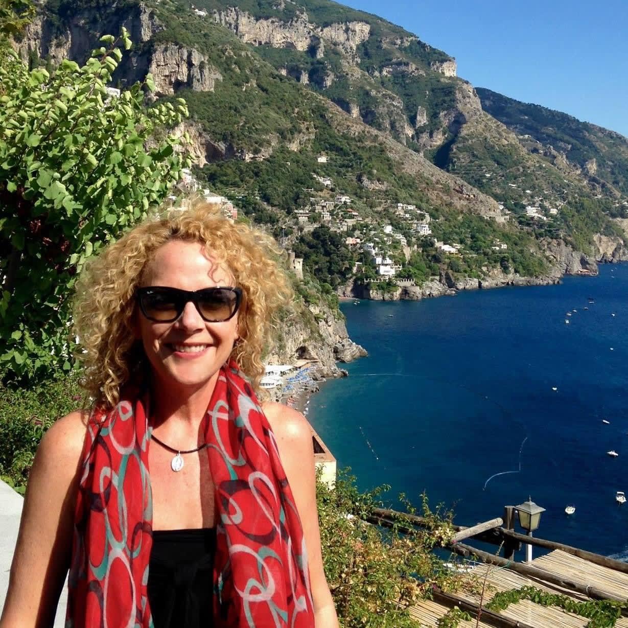 Picture of Melody wearing a pink shawl with cliffs and a sea view behind her