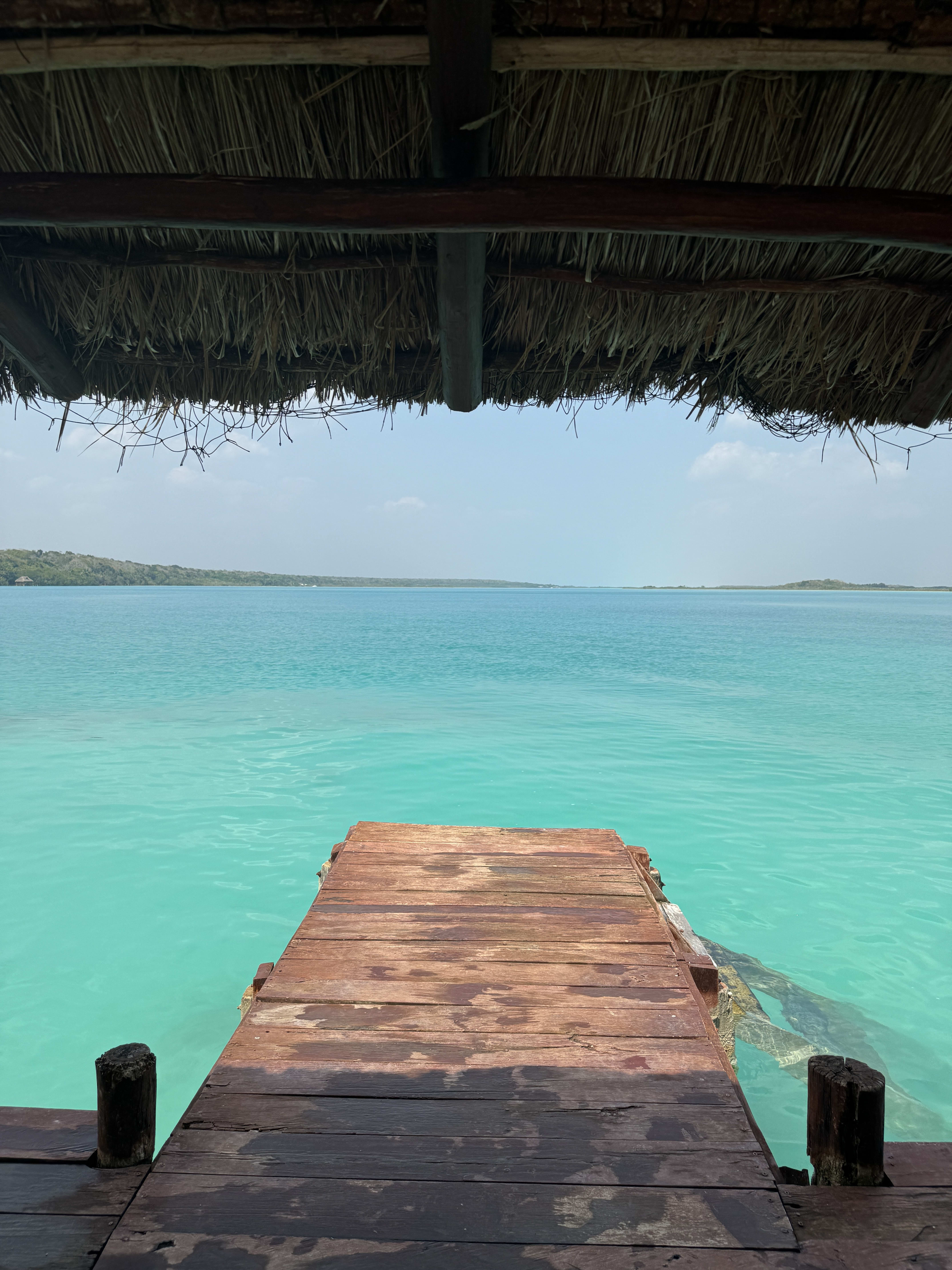 View of the end of a wooden dock stretching out to a bright turquoise ocean