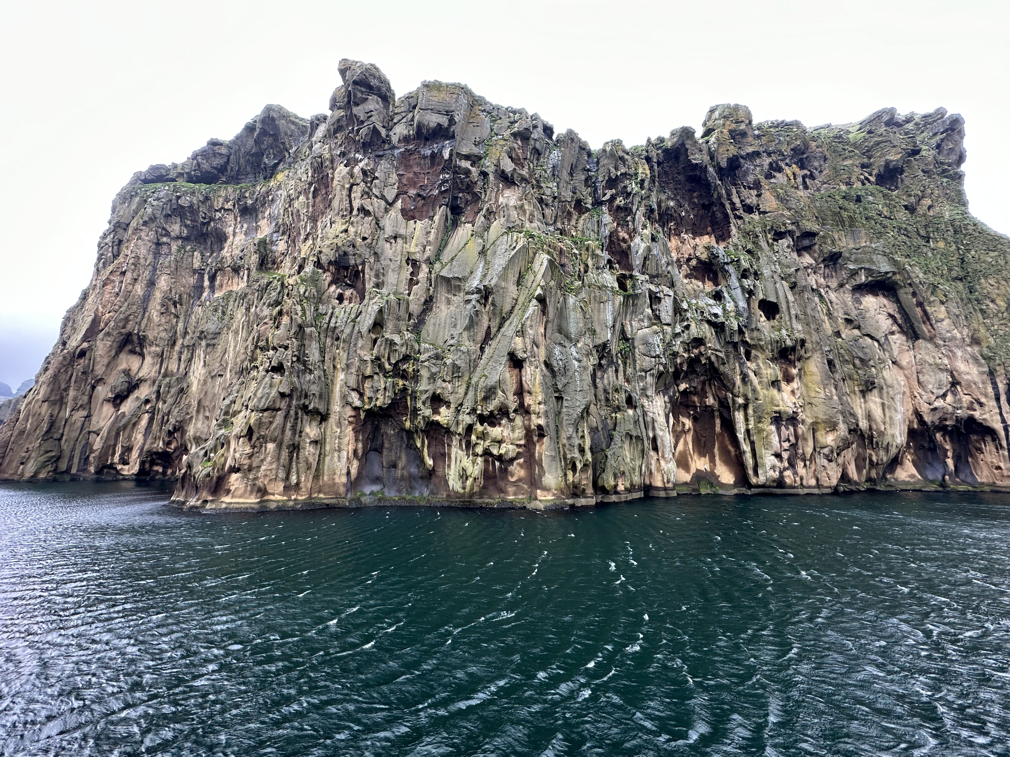 Beautiful view of a large rock formation emerging from a dark sea on a cloudy day
