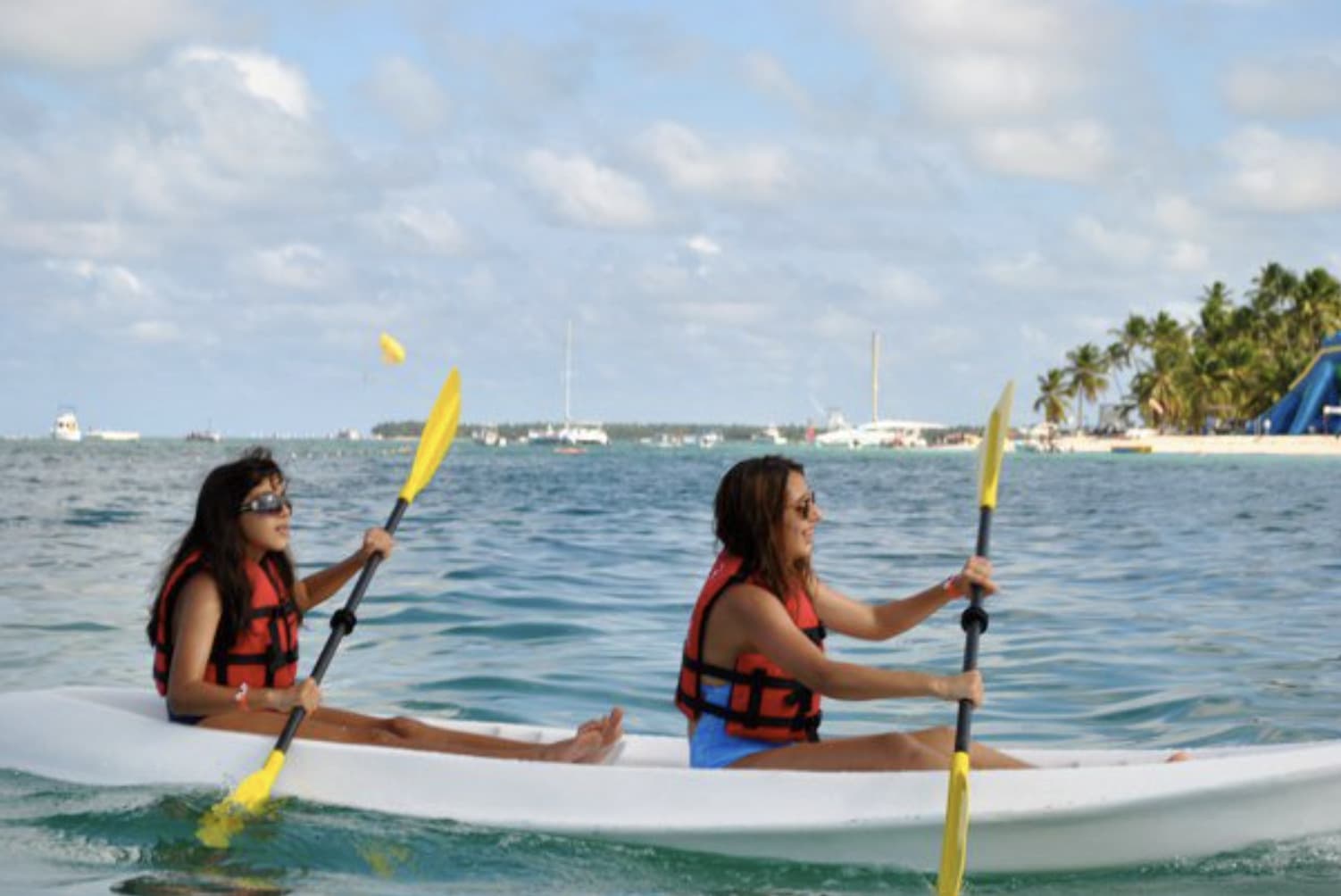 Annabelle and a friend kayaking on the ocean with boats in the background