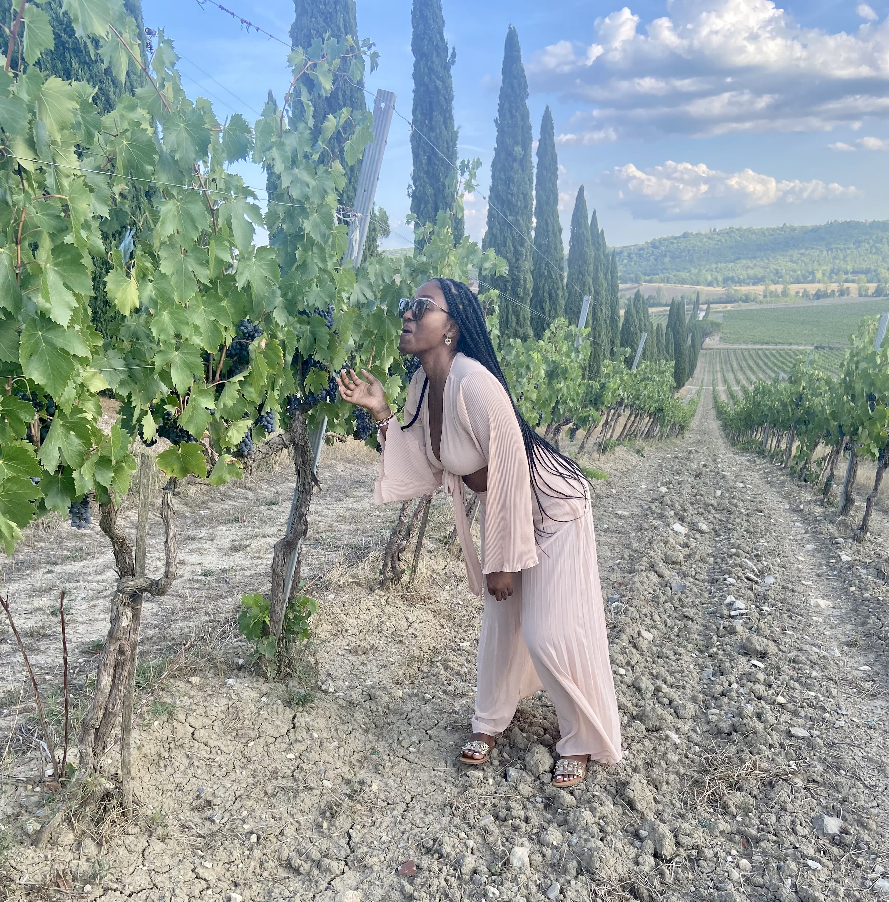 Chardon posing next to grape vines in a pastel pink dress.