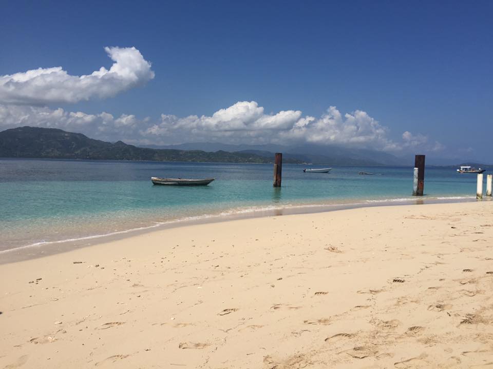 Beautiful view of an empty beach with a small boat floating on crystal clear water on a sunny day