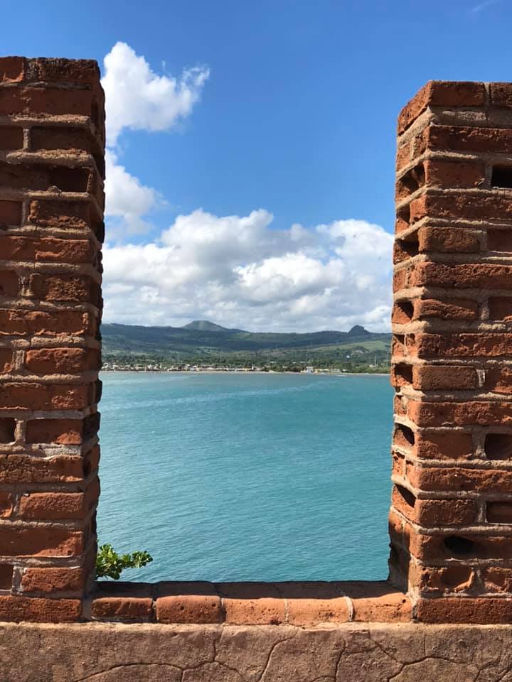 View of the ocean on a sunny day as seen through a gap in a brick wall