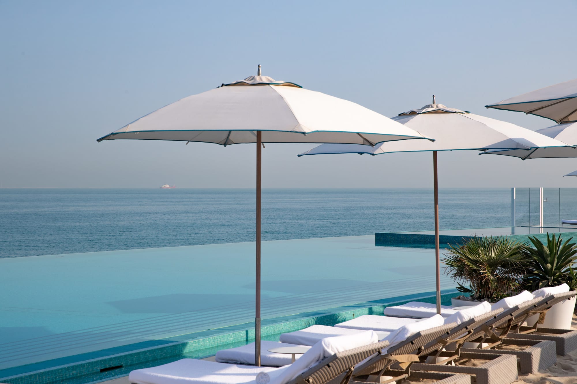 infinity pool with umbrellas and loungers overlooking the ocean