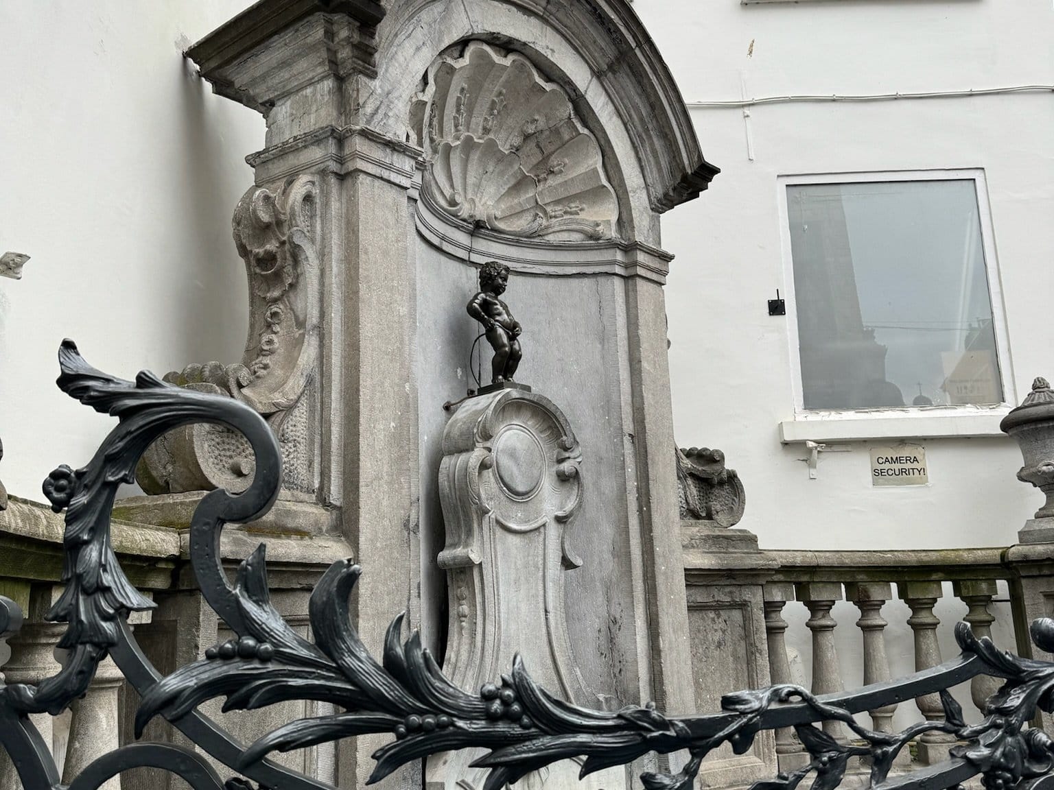A small bronze statue of a boy urinating in a fountain, known as Manneken Pis, in Brussels