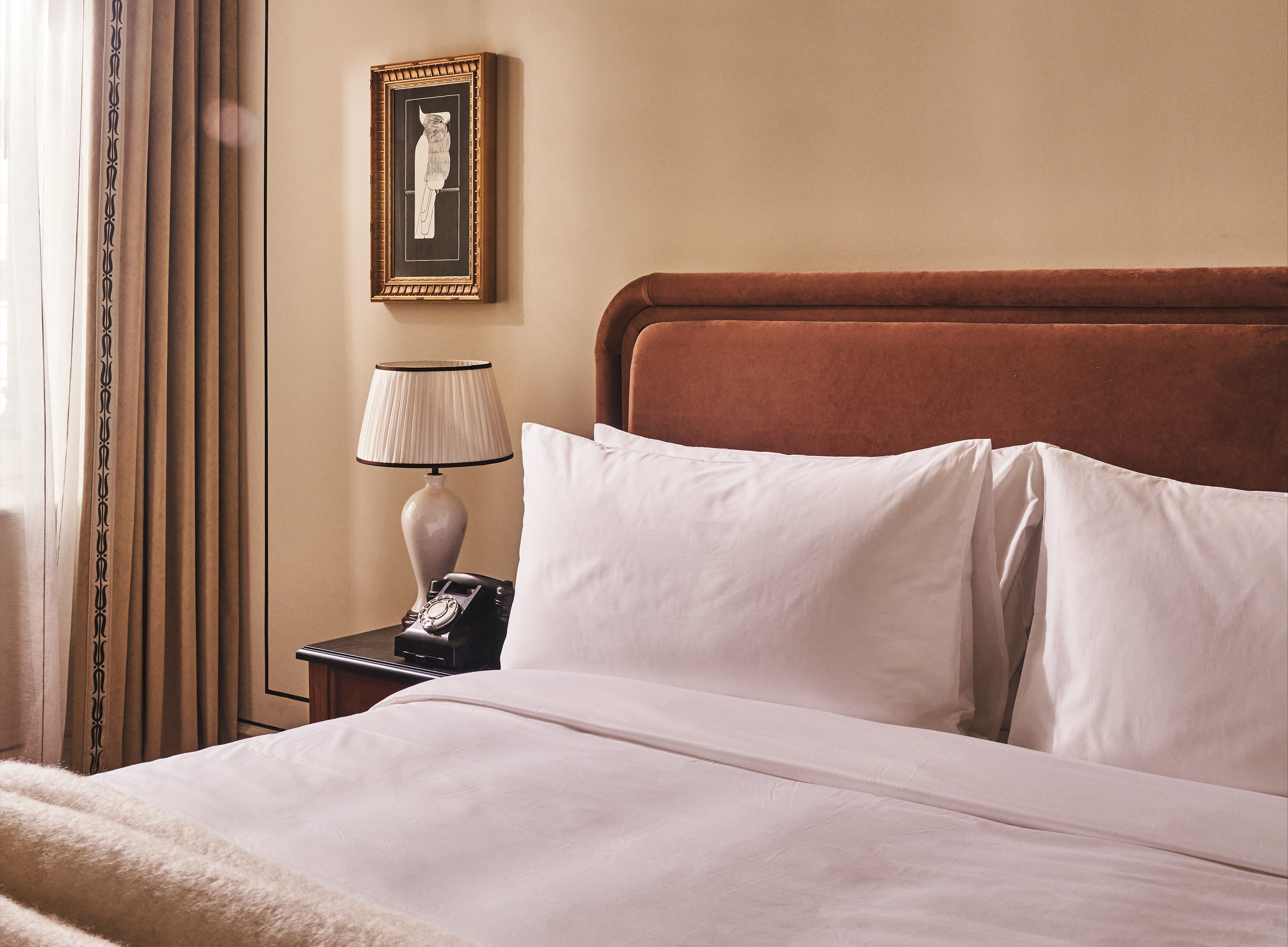 a luxe hotel room bed with a suede brown headboard