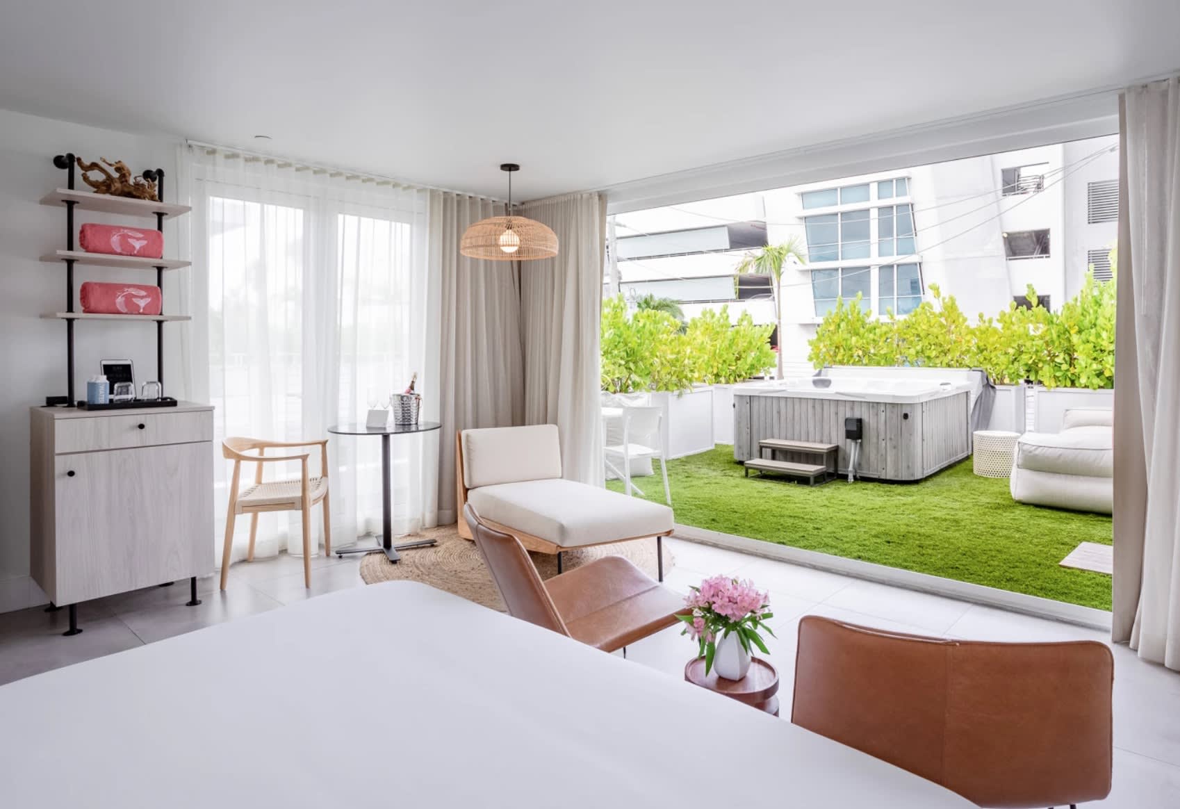 white bedroom with large terrace with turf and a hot tub