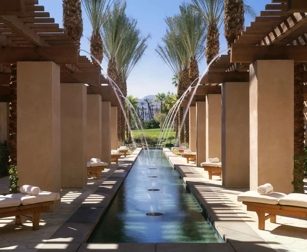 a reflective pool amid sand-colored columns in the desert