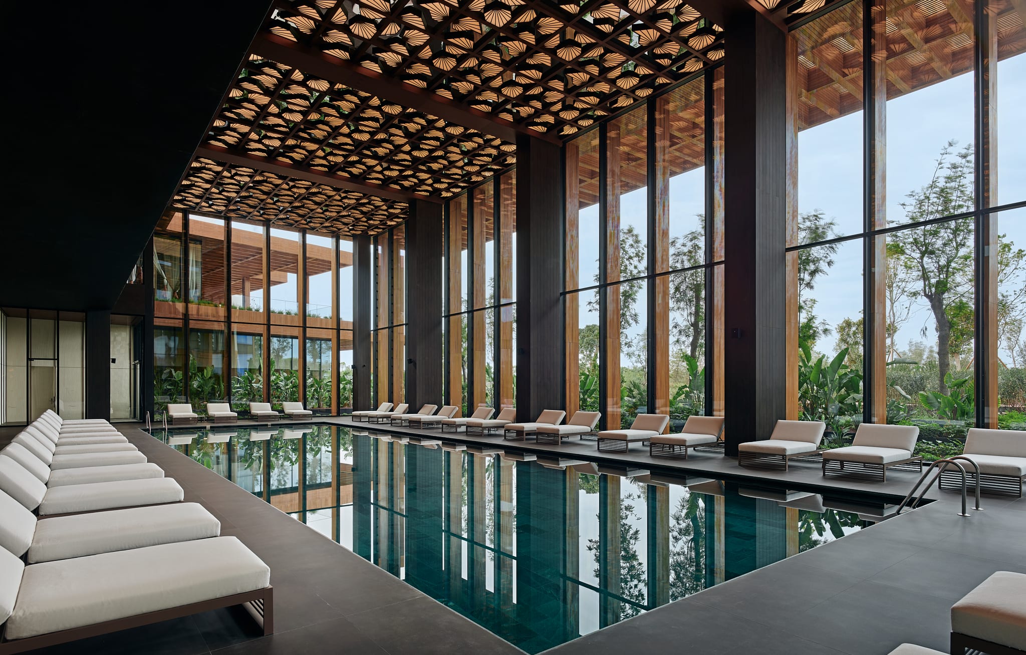a fancy indoor pool surrounded by white lounge chairs