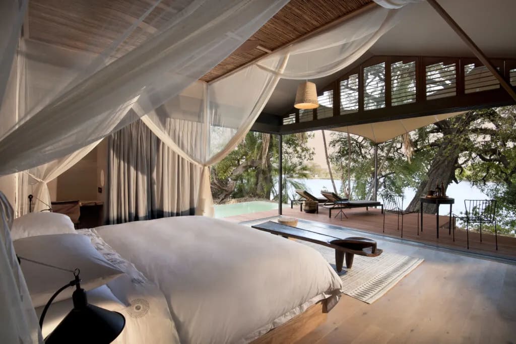 a luxe safari bedroom with a four-post bed overlooking the jungle