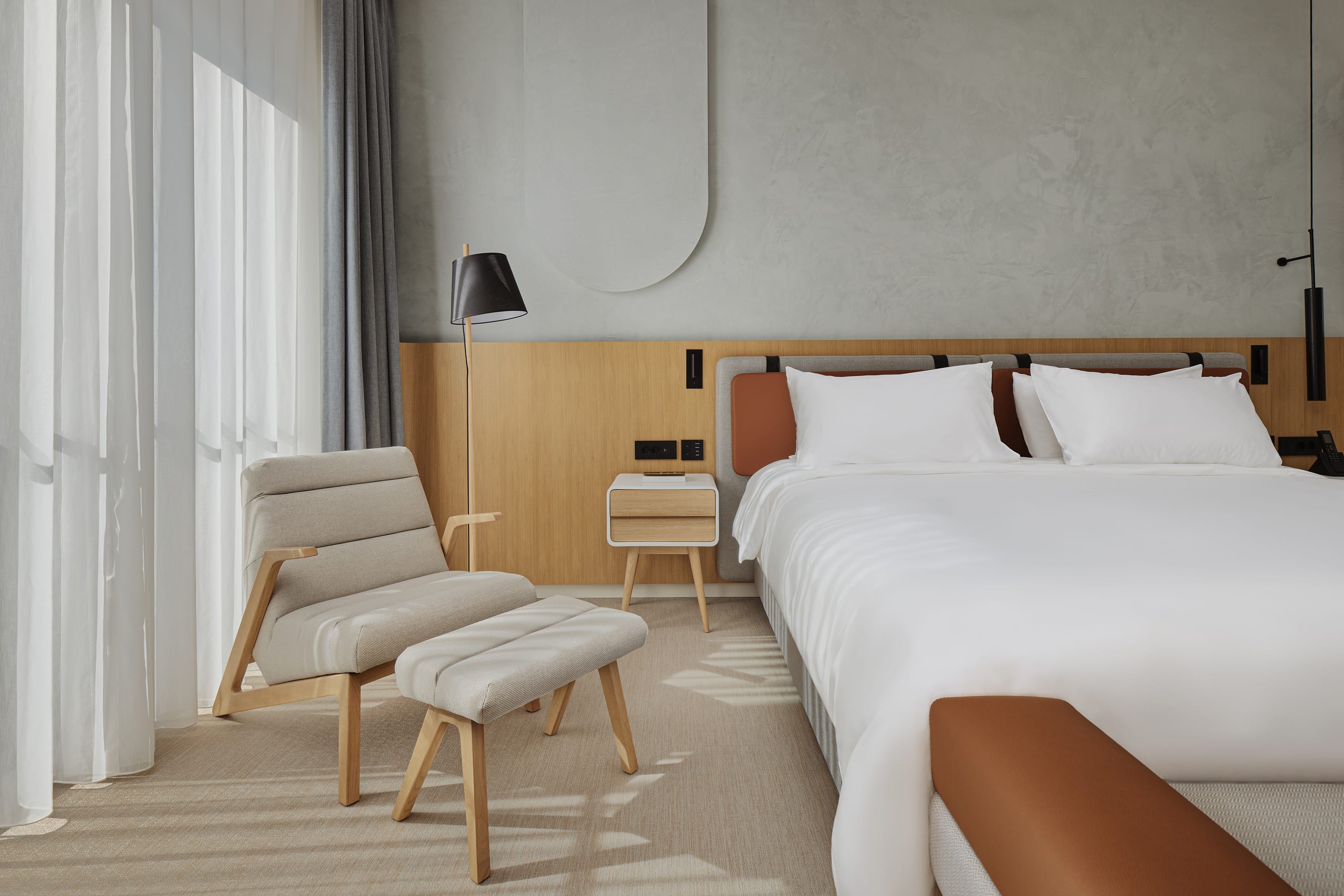 A suite showing a bed with modern armchair and wood and leather furnishings and fixtures and neutral decoration