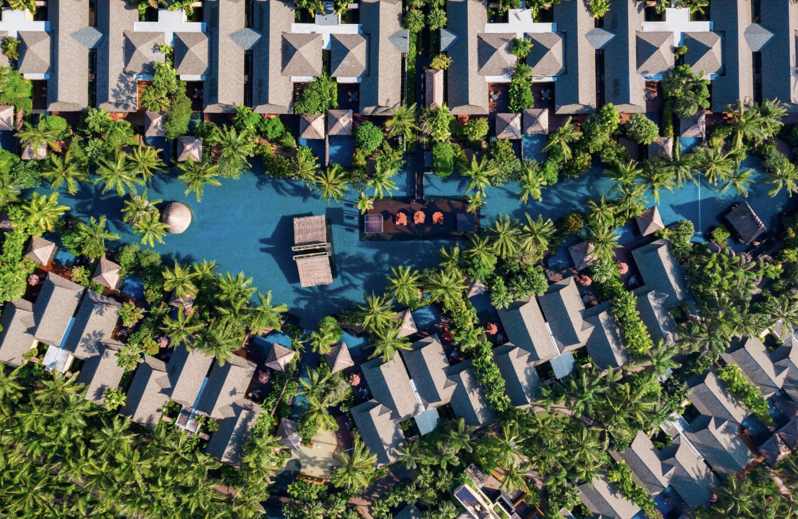 Aerial view of a hotel with villas around a lagoon and greenery