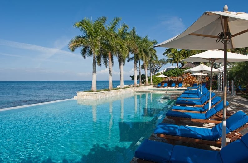Infinity pool with blue sun loungers and palm trees