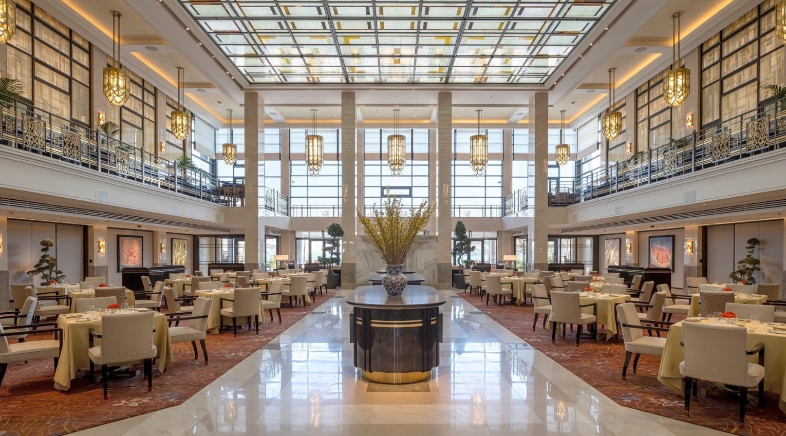 lobby with tables and chairs, a tall ceiling and lots of windows