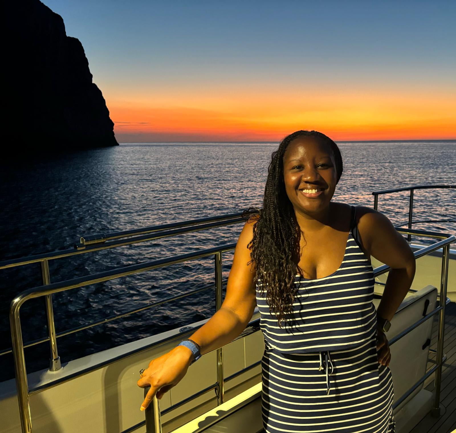 woman standing on a boat with golden sunset behind