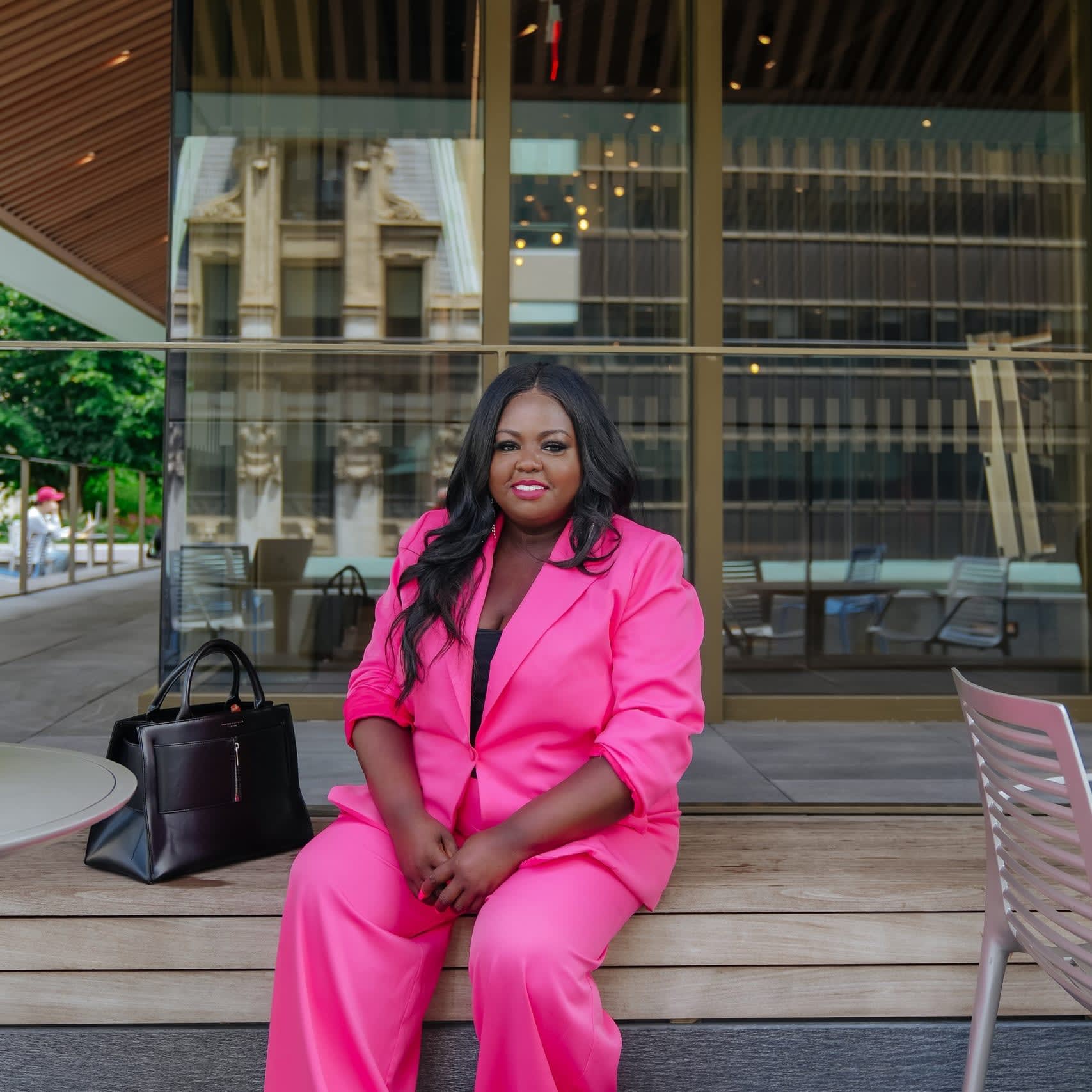 woman in pink sitting outside on steps in front a building