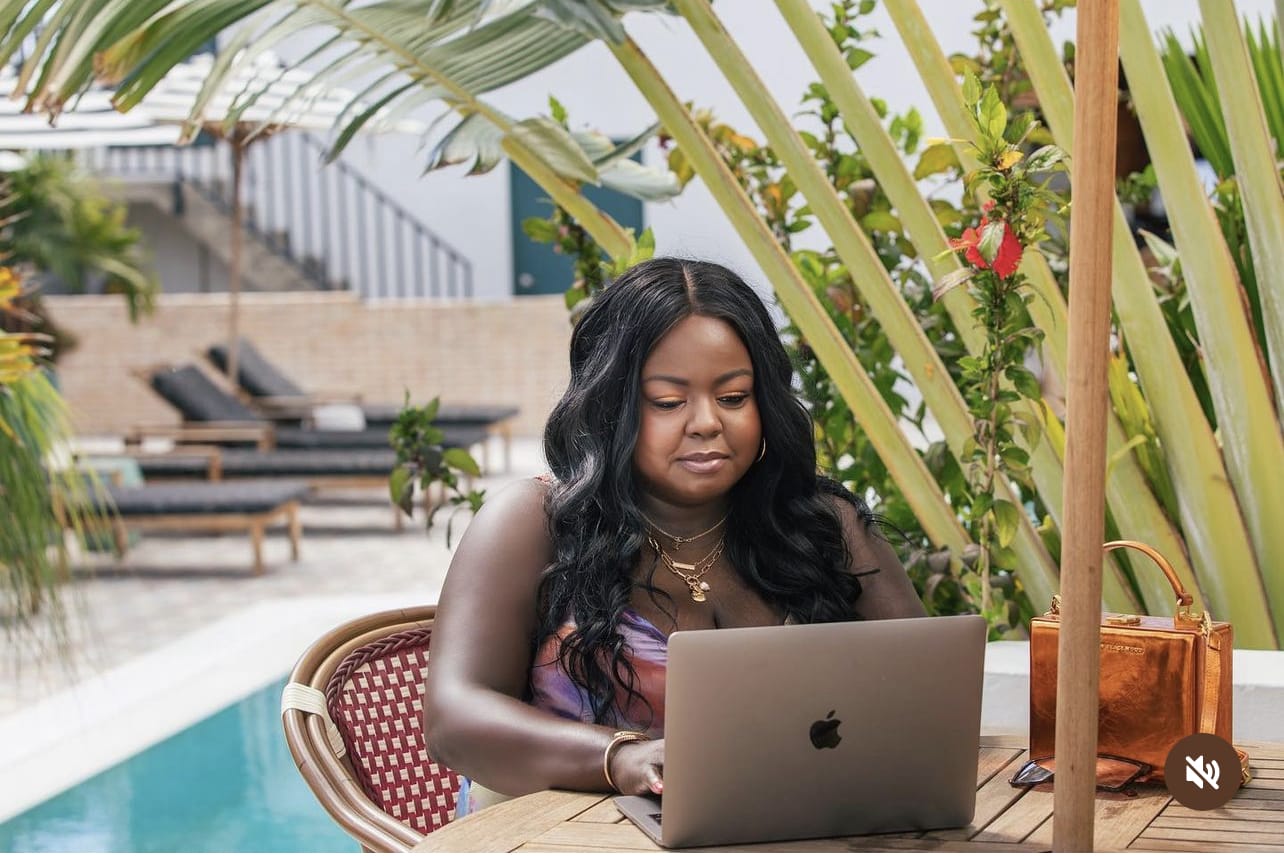 woman sitting poolside at a table working on a computer