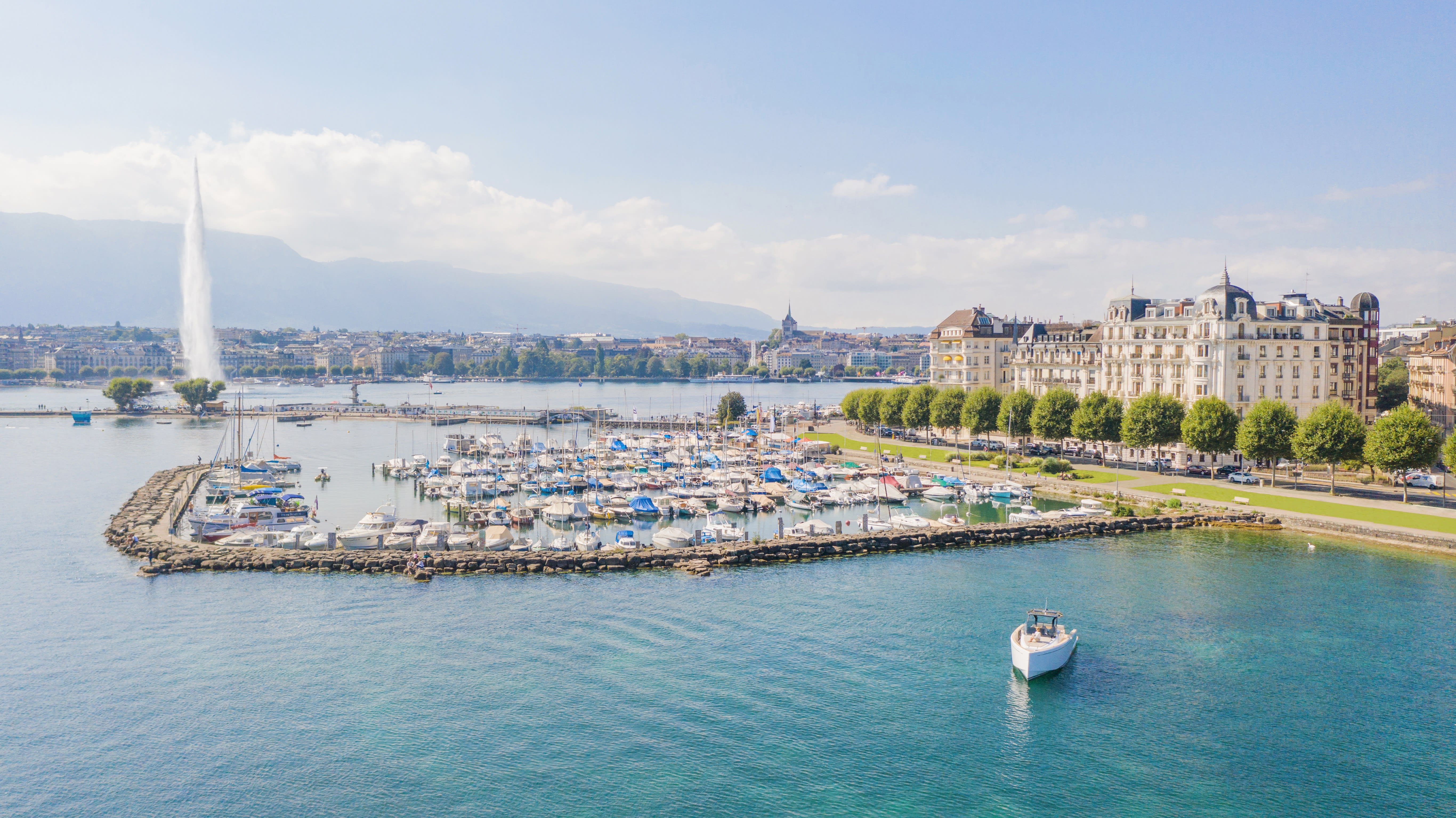A view of a large lake with marina and grand hotel building surrounded by gardens