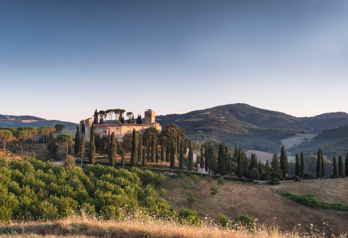 Italian landscape with hills, tall cypress trees and a castle