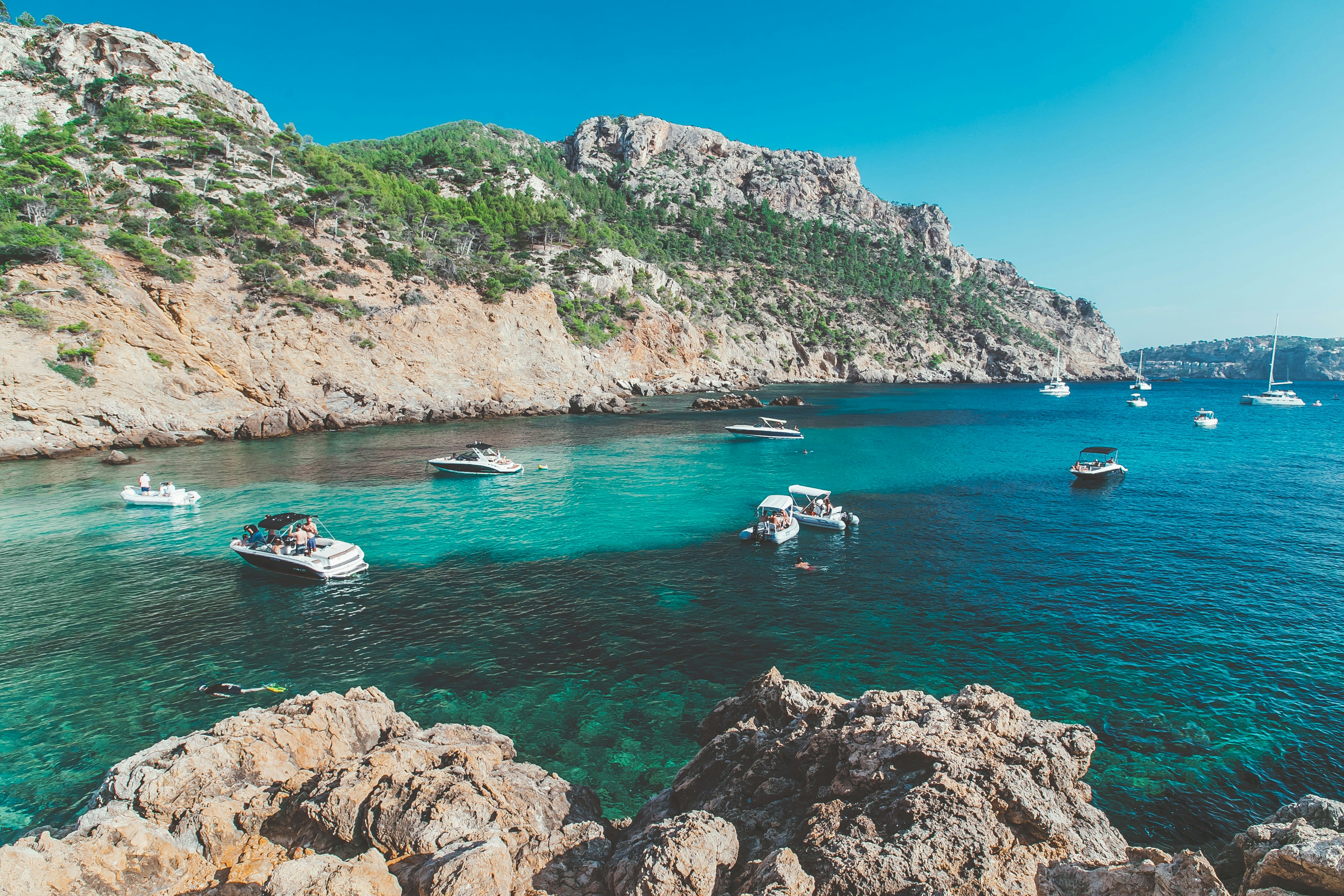 Turquoise ocean with boats and surrounding cliffs
