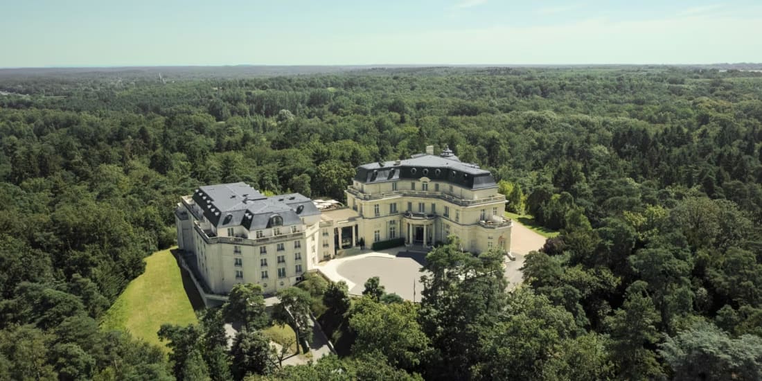 aerial view of a grand palace amid an expanse of trees