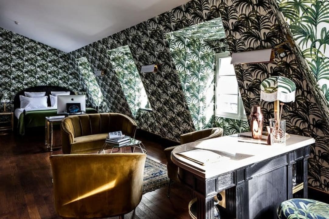 A hoetl room with green and white wallpaper and velvet seating.