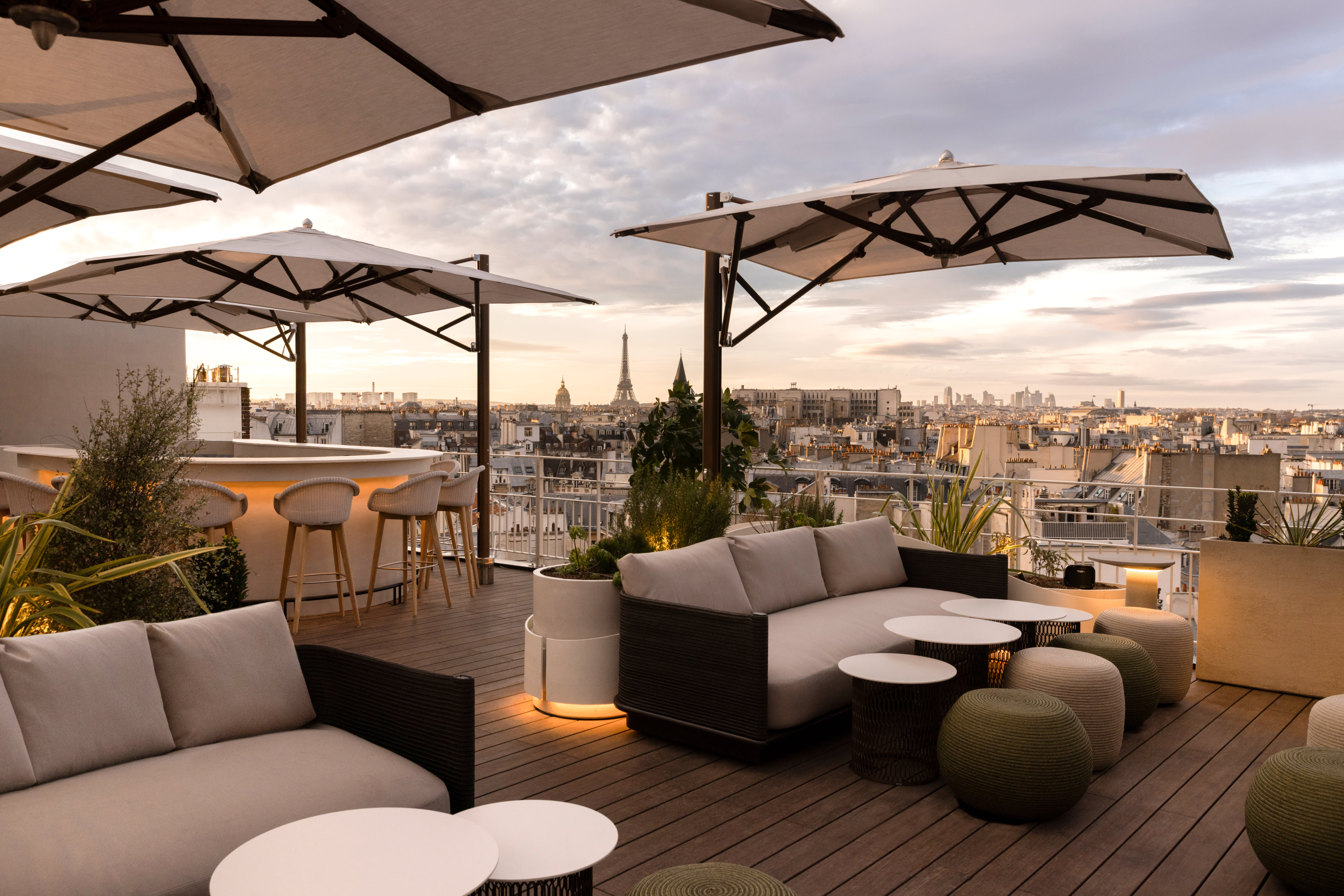 Rooftop area with lounge seating at dusk overlooking Paris