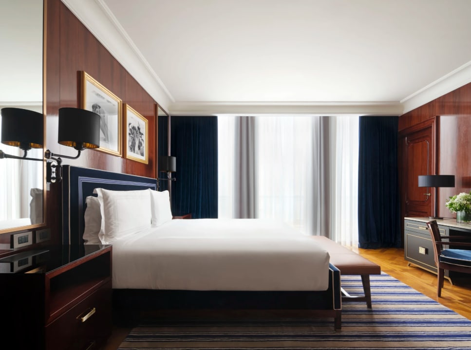 An elegant hotel room with a chandelier, dark, antique furnishings and high ceilings