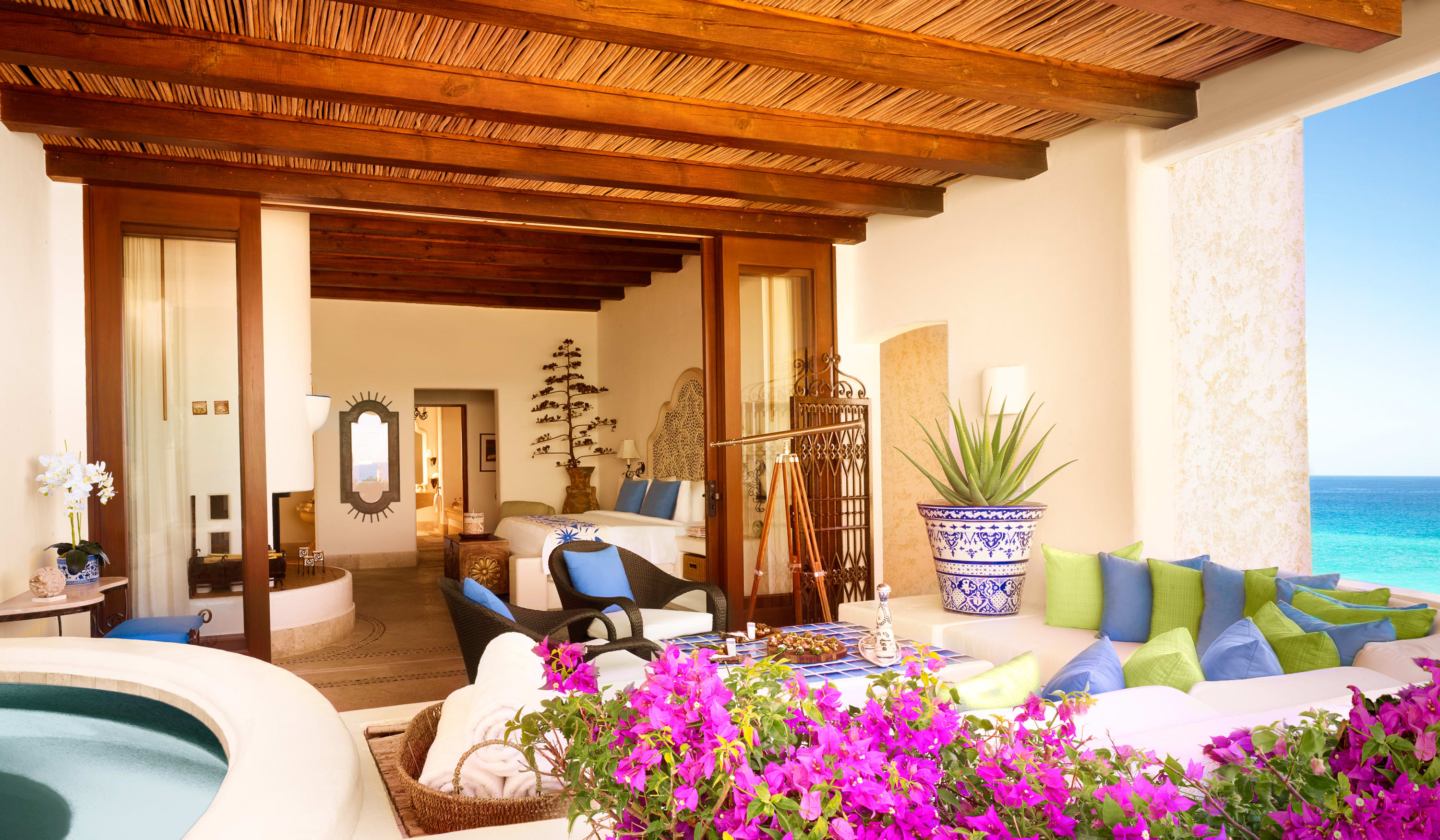 A view from the balcony of a hotel suite with traditional Mexican design, pink flowers and a plunge pool.