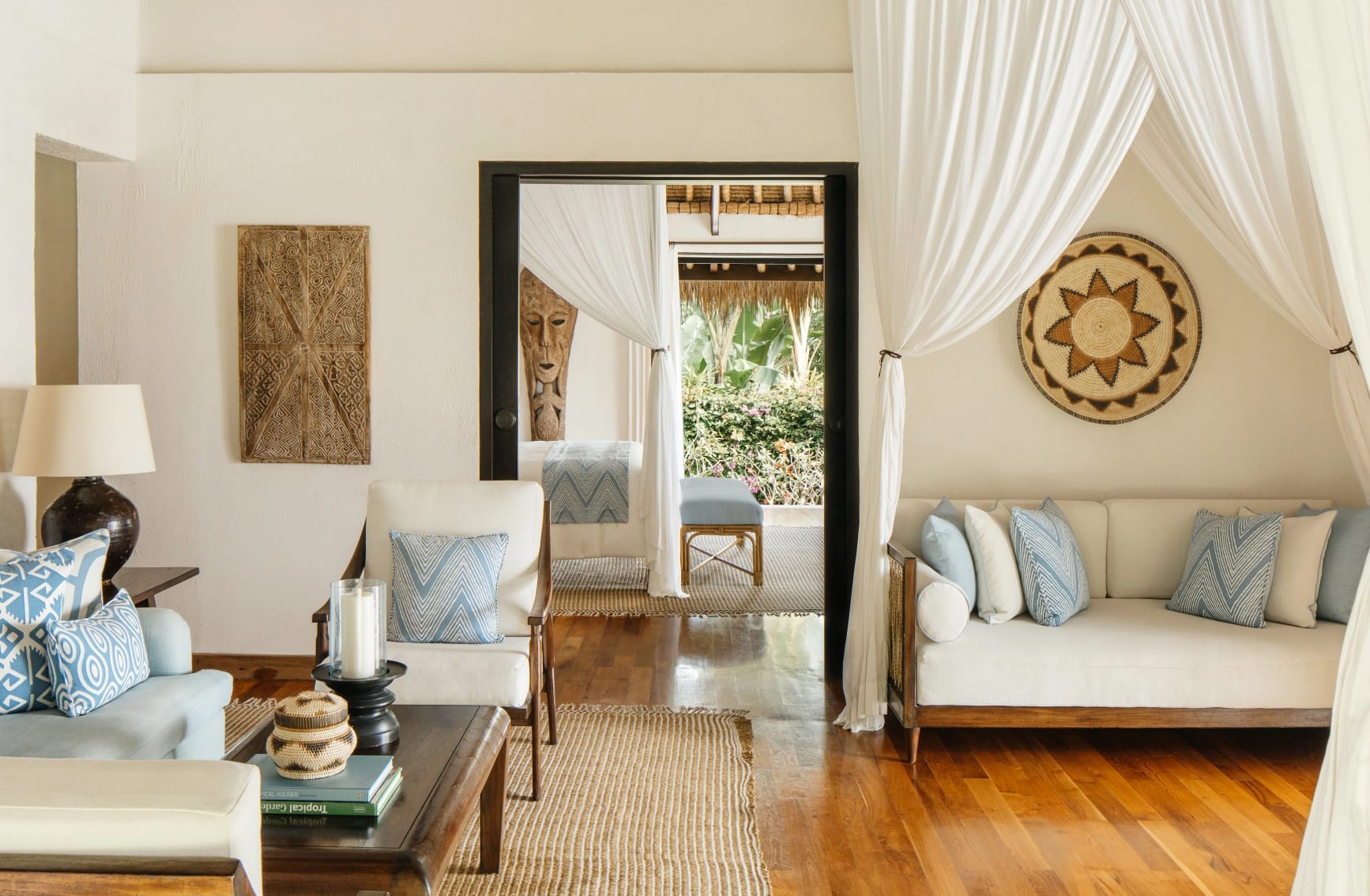 An elegant living room of a hotel villa with natural tones, wooden floor and tribal artwork.