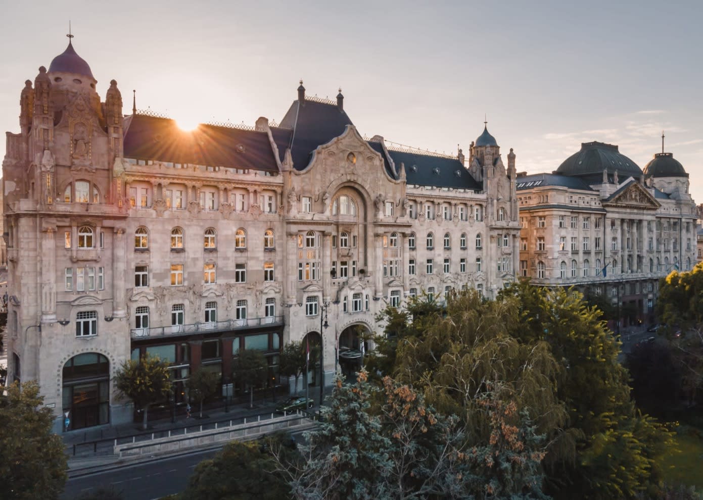 impressive palace with gray slate roof with sun over the top and a green park in front