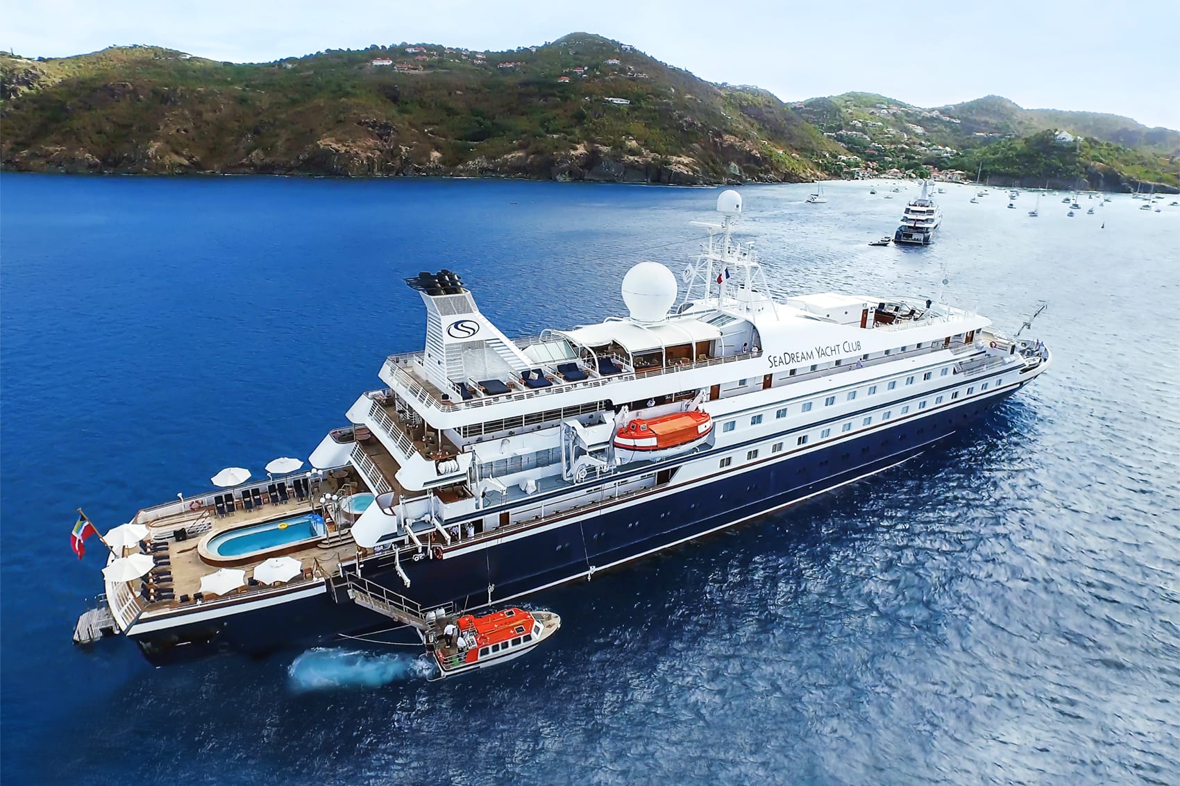 Arieal view of yacht cruise docked offshore a green hill covered island