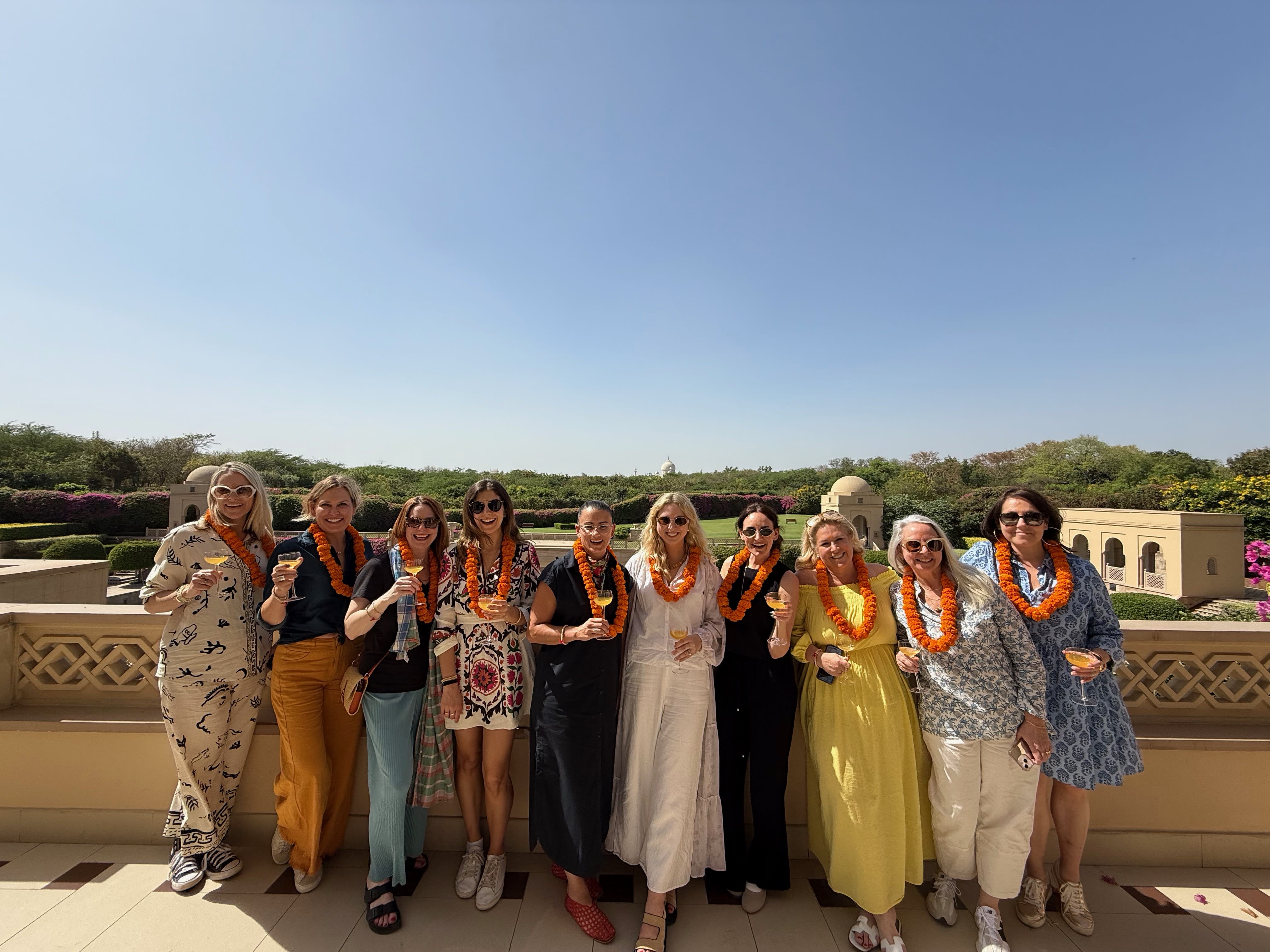 a group of women stand in a row on a sunny terrace in India