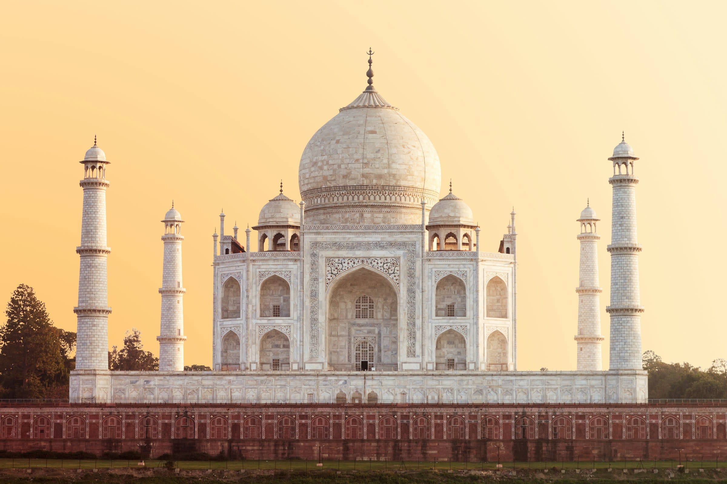 ornate white and brown stone domed building with spires at each corner bathed in golden light