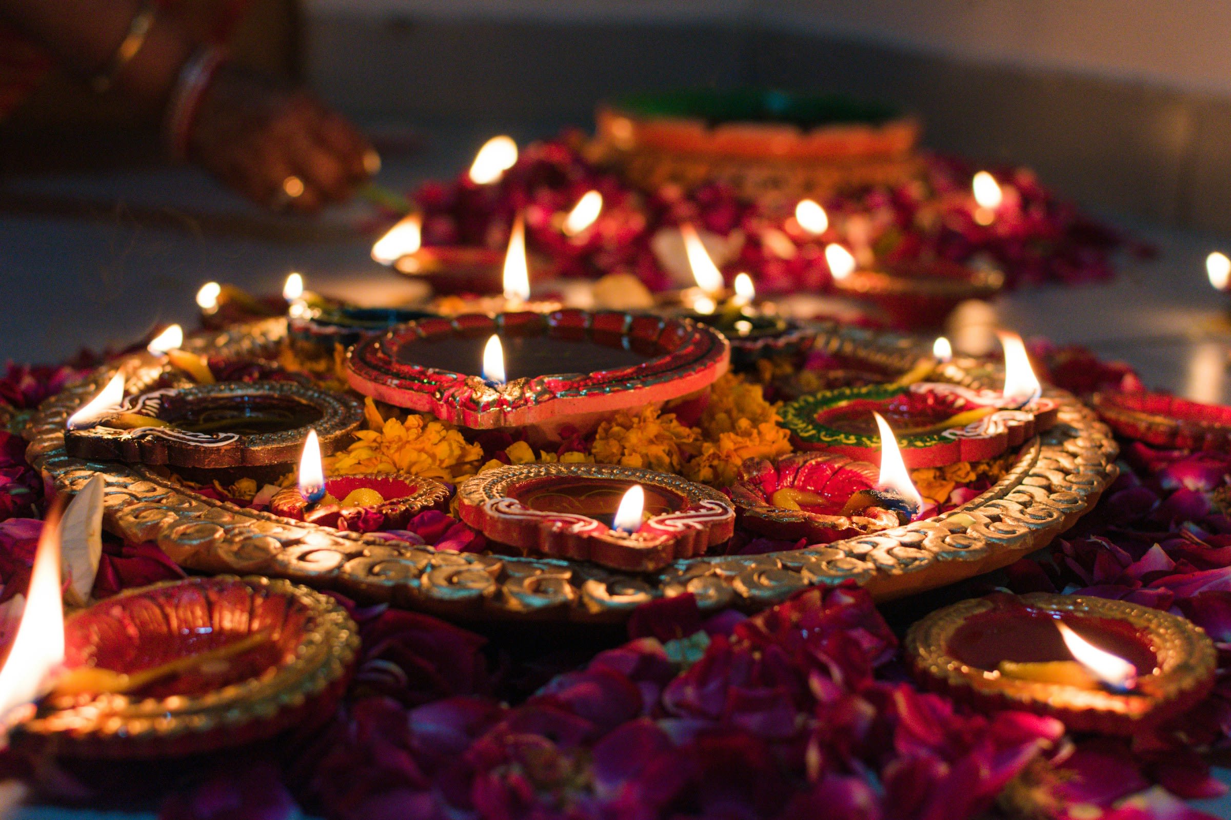 Several lit candles in dim lighting surrounded by carved wood and hues of red, yellow and gold