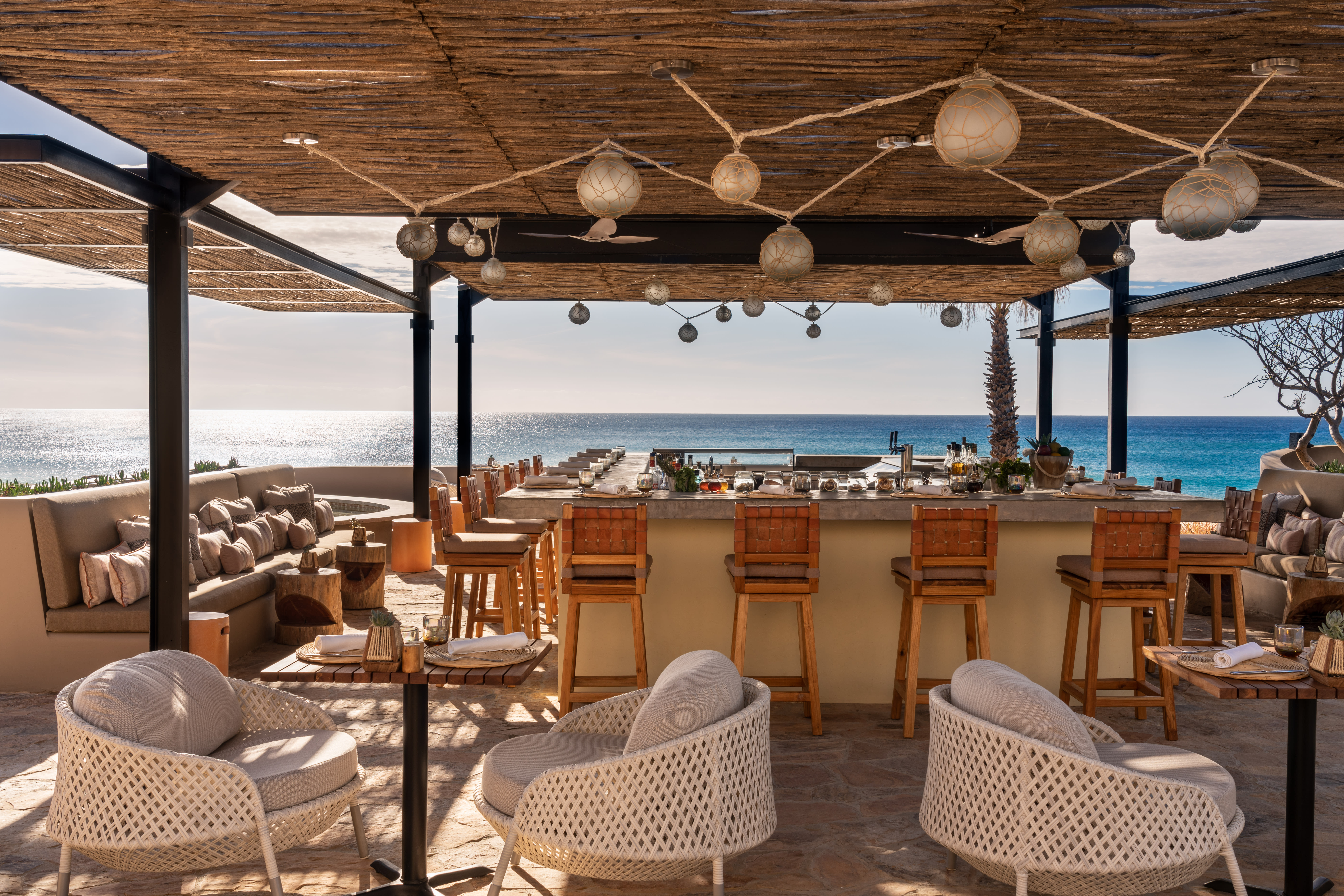 An outdoor bar area at a hotel with cream and wooden furnishing and sea views