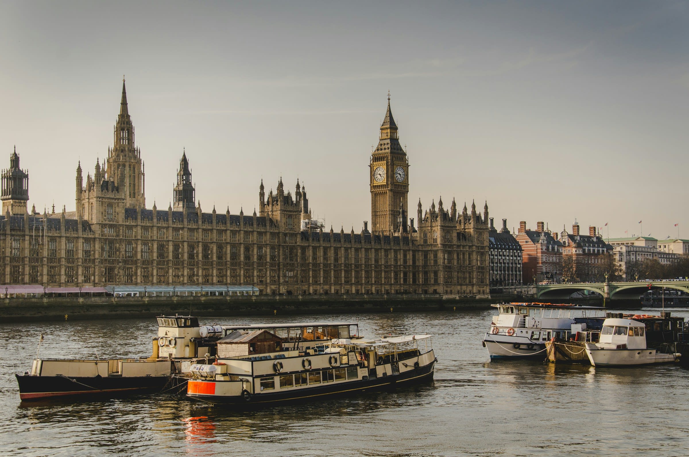 boats on a river during daytime with historic, ornate buildings with towers on the banks behind the river