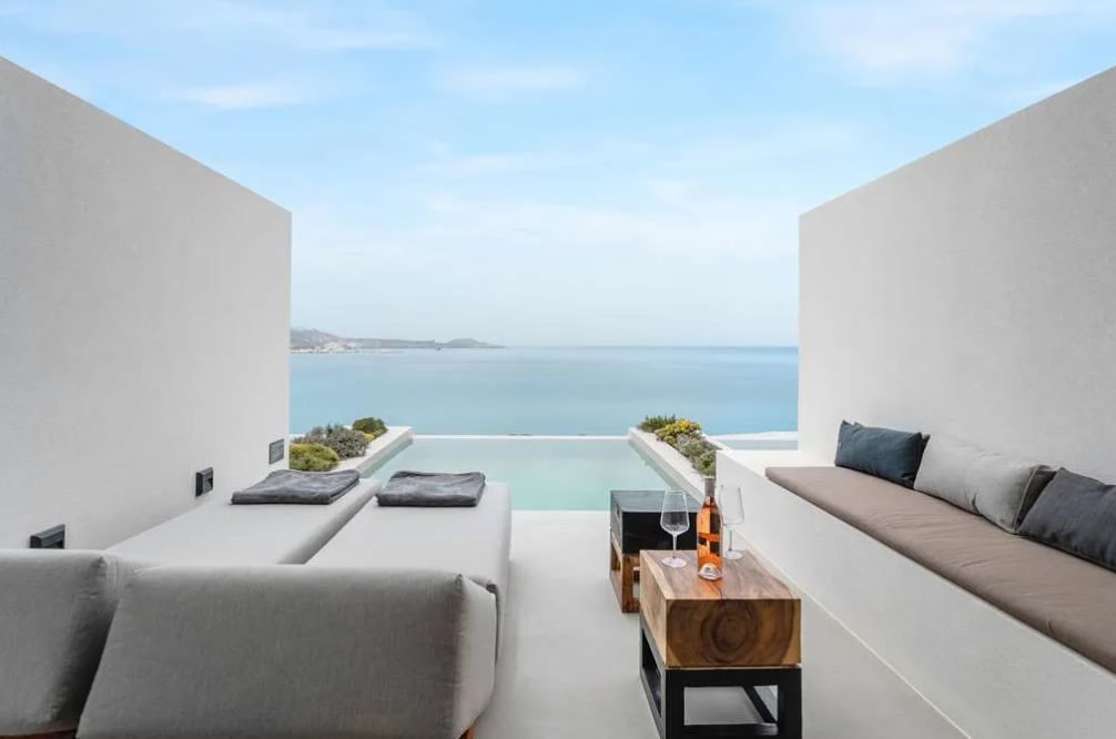 A sleek all-white hotel terrace with a plunge pool facing the ocean