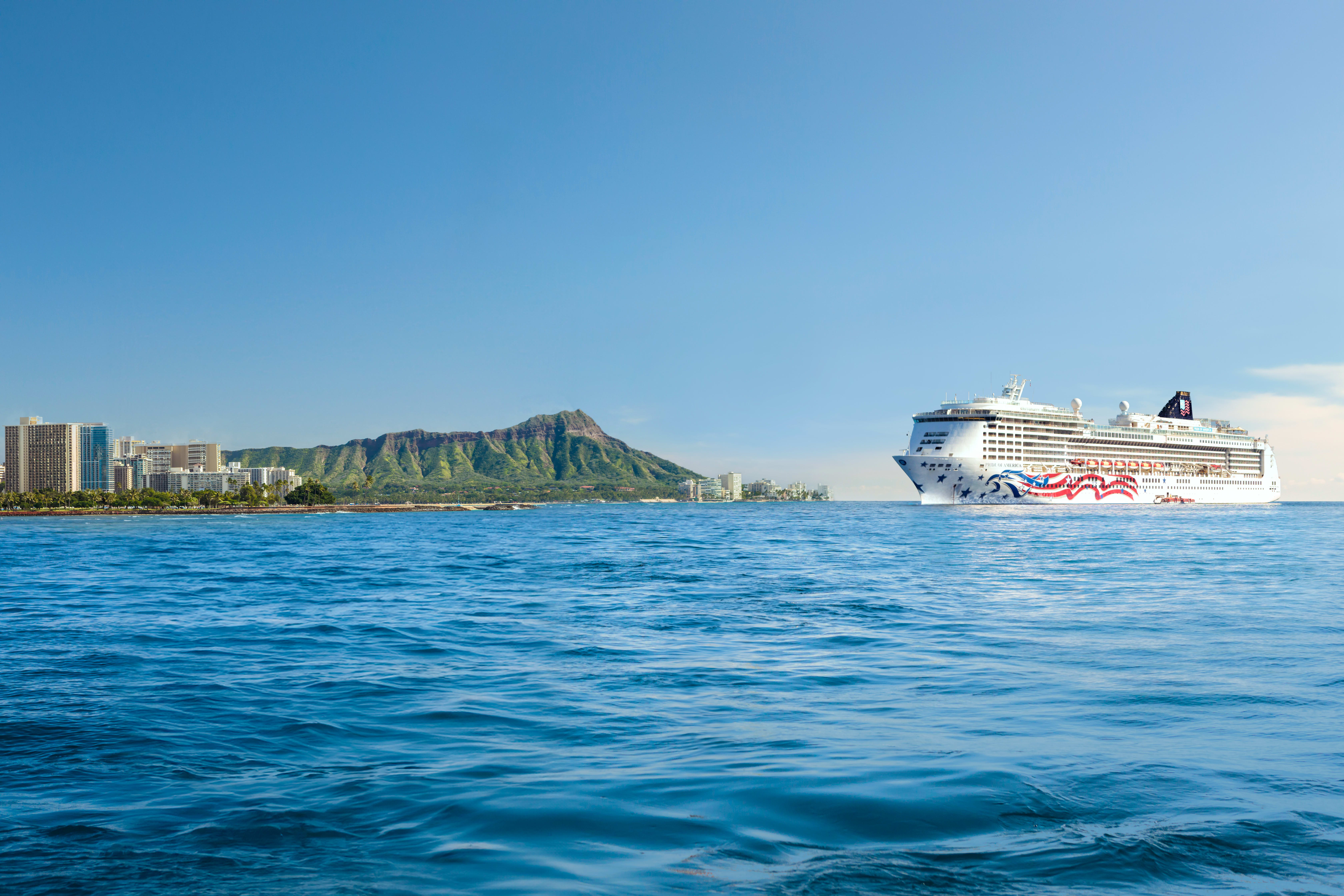 Blue ocean waters with cruise ship off to the right in the distance with a tropical island to the left during day