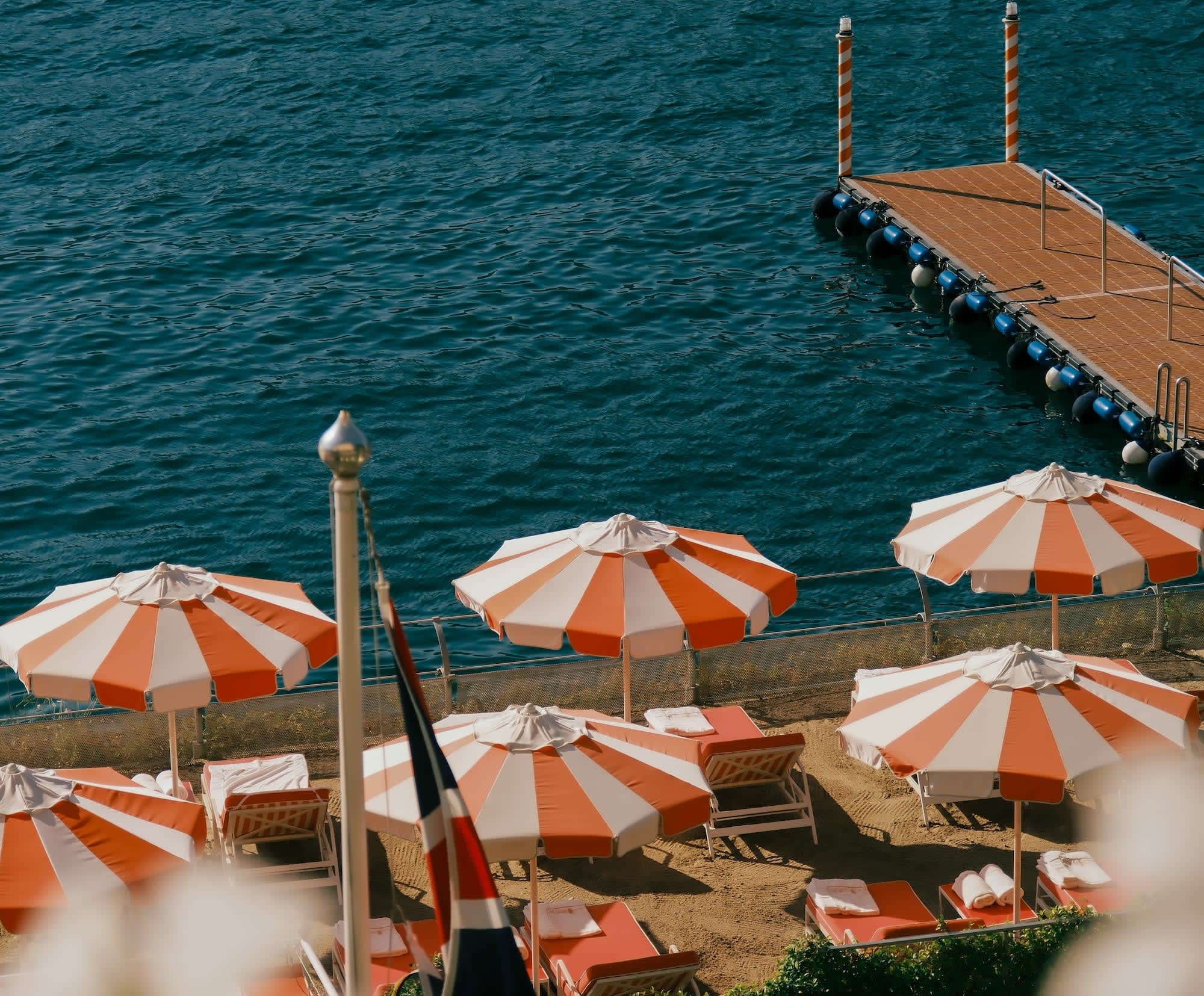 orange-and-white striped umbrellas on an ocean dock