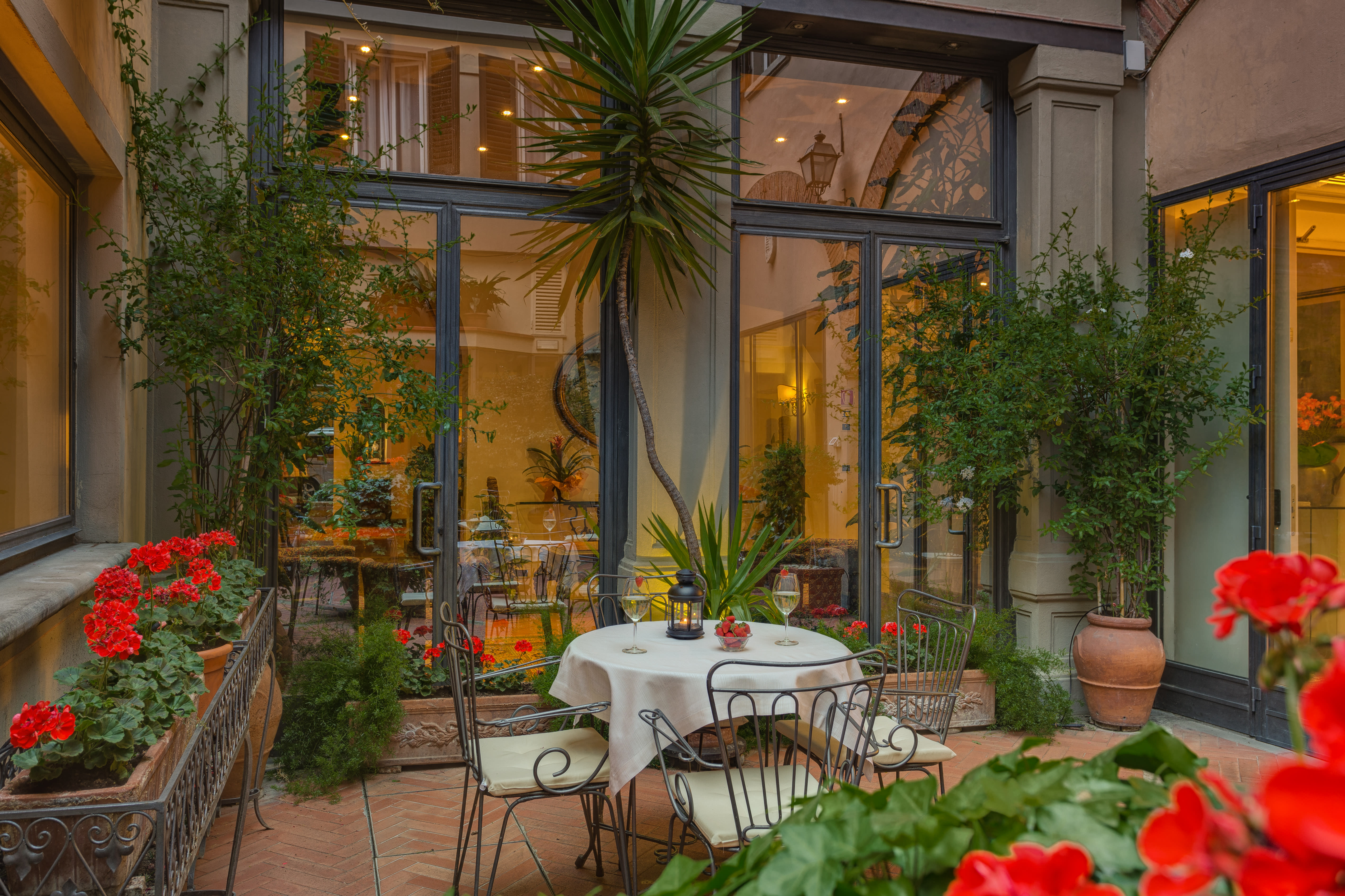 A pretty interior courtyard with dining set up and red flowers and foliage